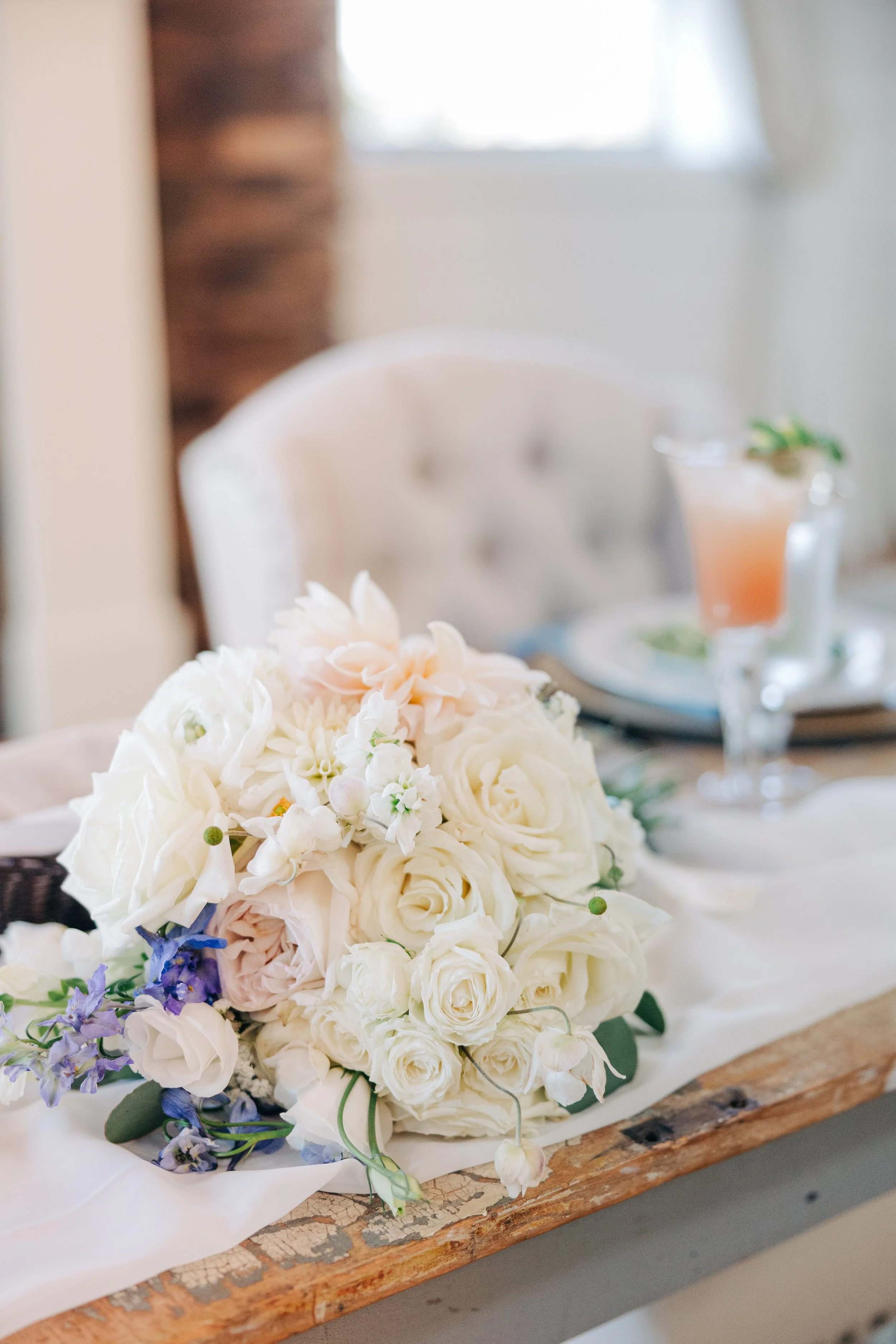 A large bouquet of white roses and other flowers on a wooden table.