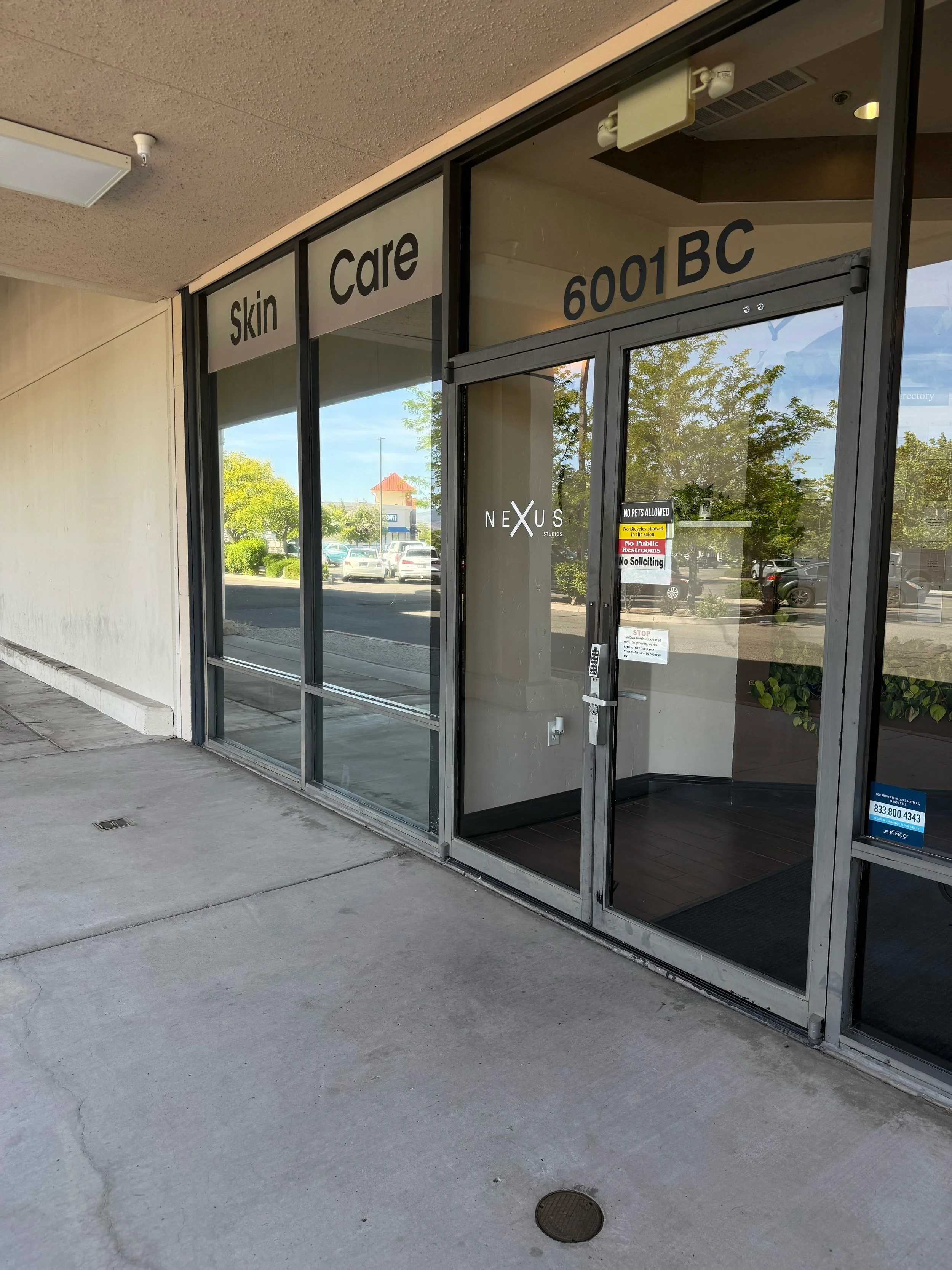 Exterior view of a skin care clinic entrance with glass doors and windows, displaying signs for 'Skin Care' and the address 6001 BC.
