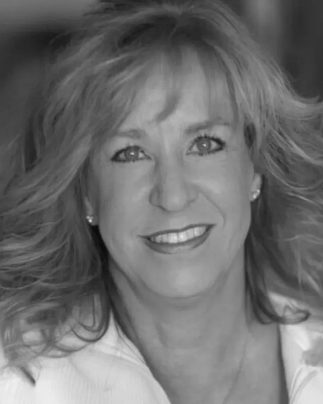 Black and white portrait of a woman with long, wavy hair smiling at the camera.