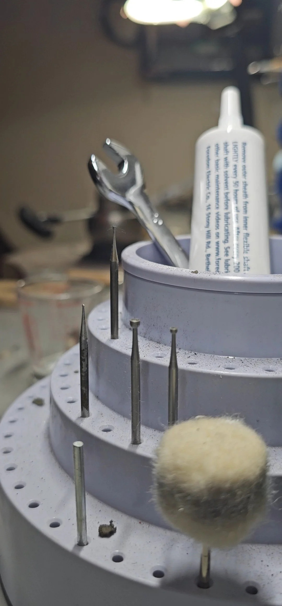 Close-up of a dental tools holder with various dental instruments, including a dental drill bit, a mirror, and a dental applicator, in a dental clinic setting.