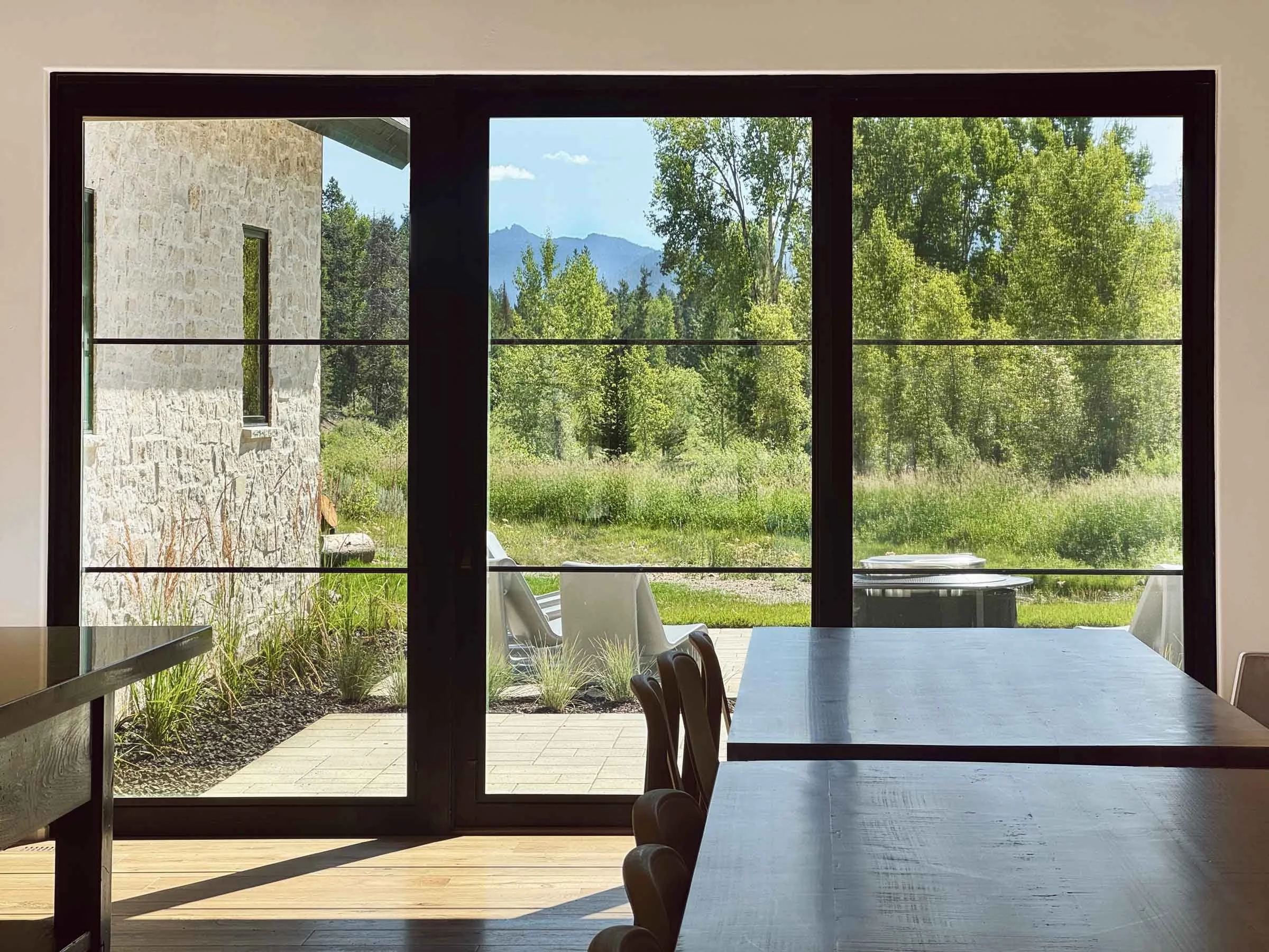 Open dining room in a custom Idaho mountain home by Jakub Galczynski with large glass doors, demonstrating structural engineering that supports expansive openings, connection to nature, and indoor-outdoor living.