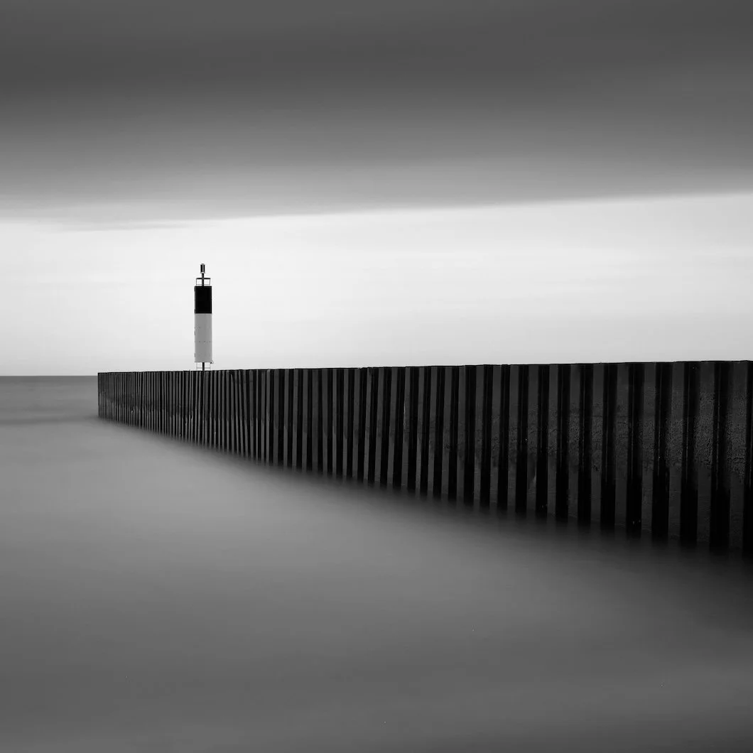 moody black and white photo of jetty with light tower in distance | stanwich painting