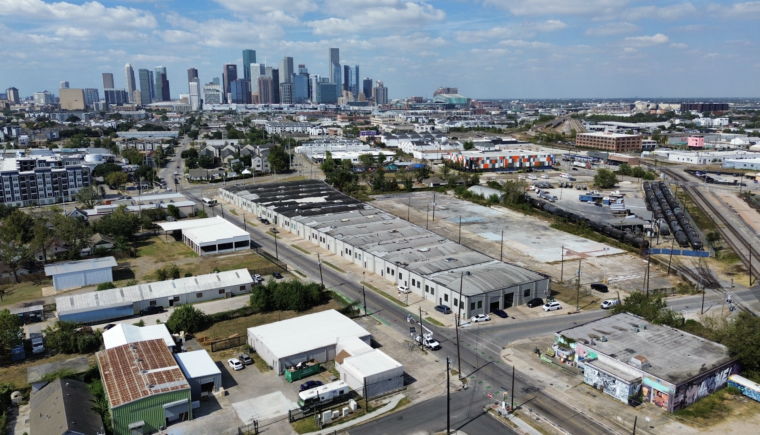 Aerial view of downtown Los Angeles with industrial area in foreground and skyscrapers in the background.