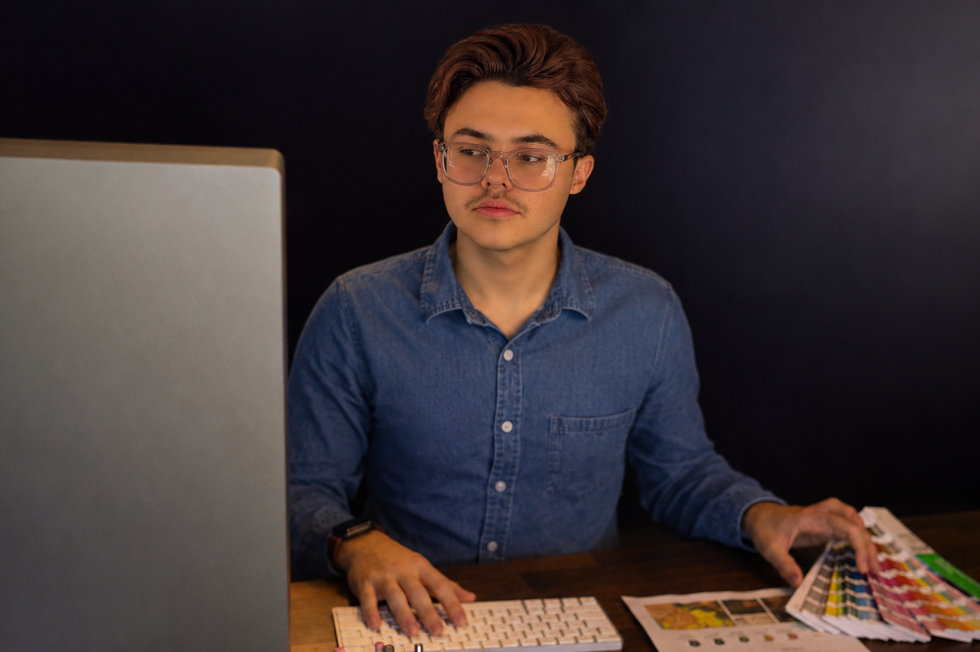 graphic designer, Dominick Cicero, working away at your next branding project, comparing color swatches and taking notes to better build your brand!