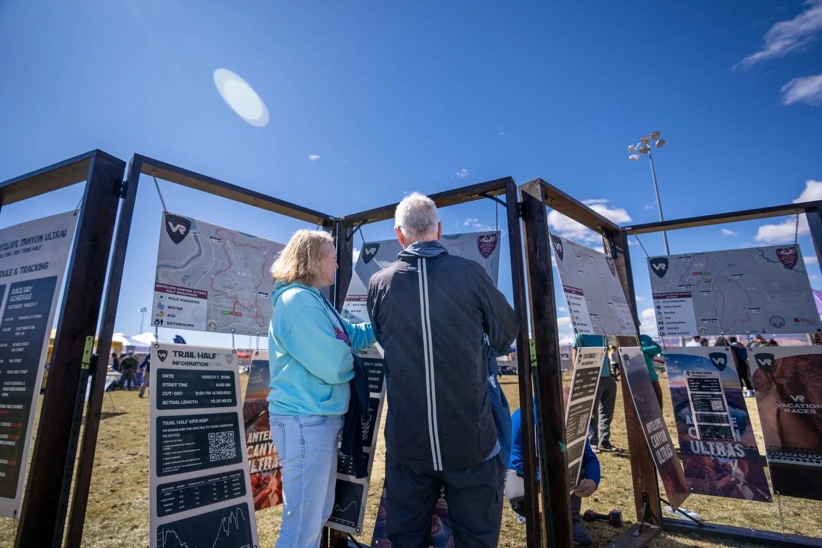 Printed race course maps by Underhill Race Maps displayed on outdoor boards, showing routes, elevation profiles, and event information.