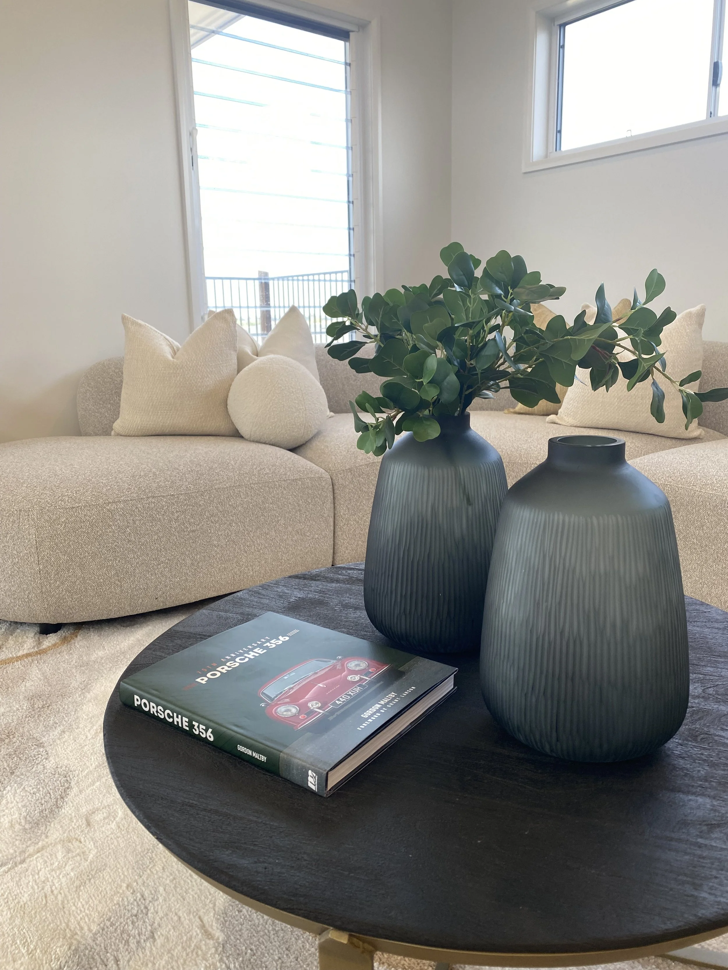 over 50s lifestyle living room styled with a corner lounge, lake views and fountain, neutral coastal interior design opposite kitchen in Hervey Bay by Styleit QLD