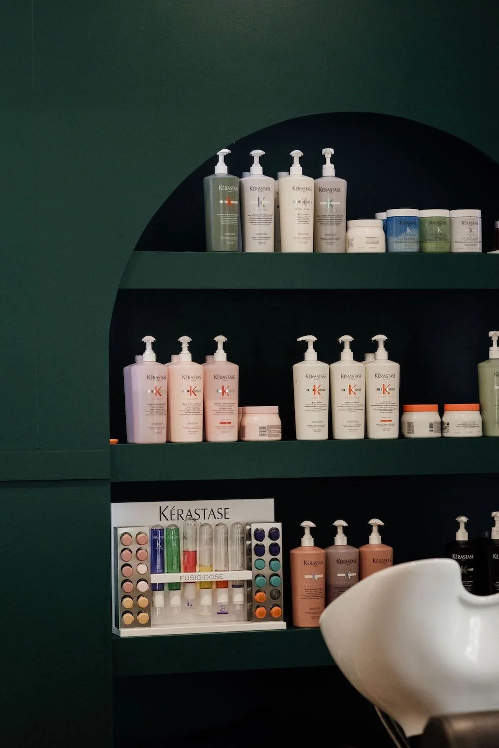 Shelves with various Kerastase hair care products, including shampoo, conditioner, and treatments, in a salon setting.
