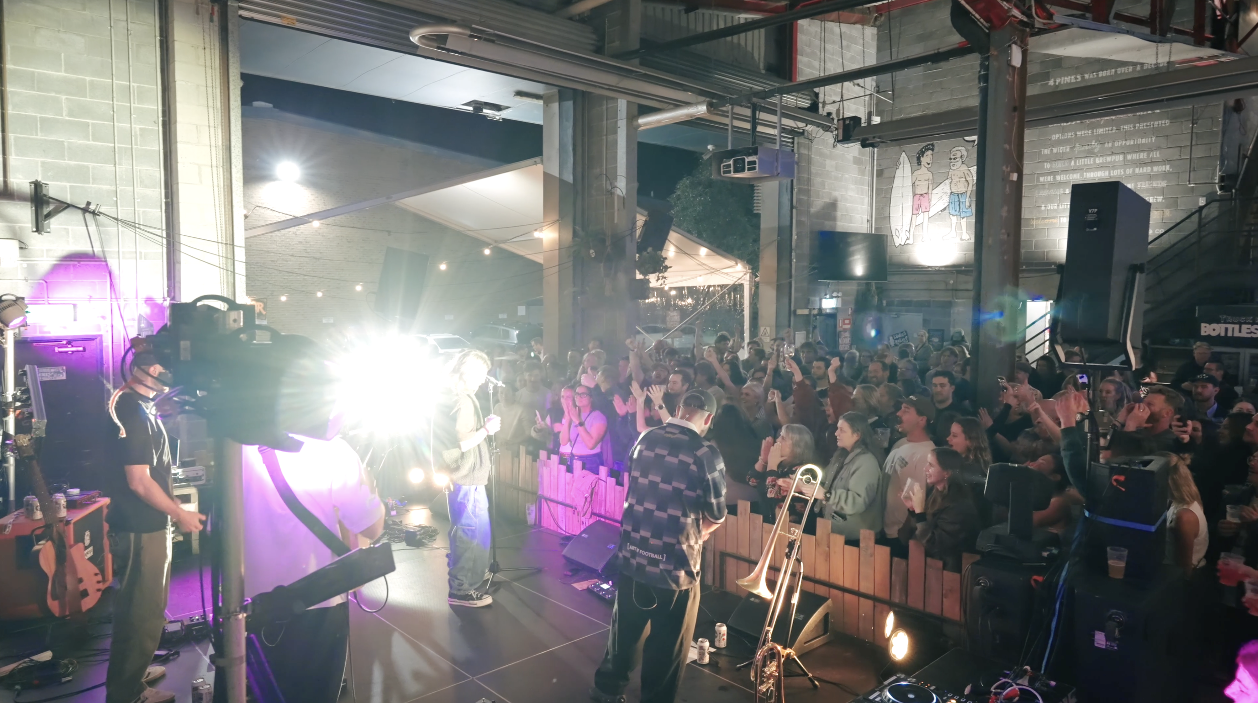 A live music performance in a lively indoor venue with a crowd enjoying the show, stage lights, musicians, and musical instruments.