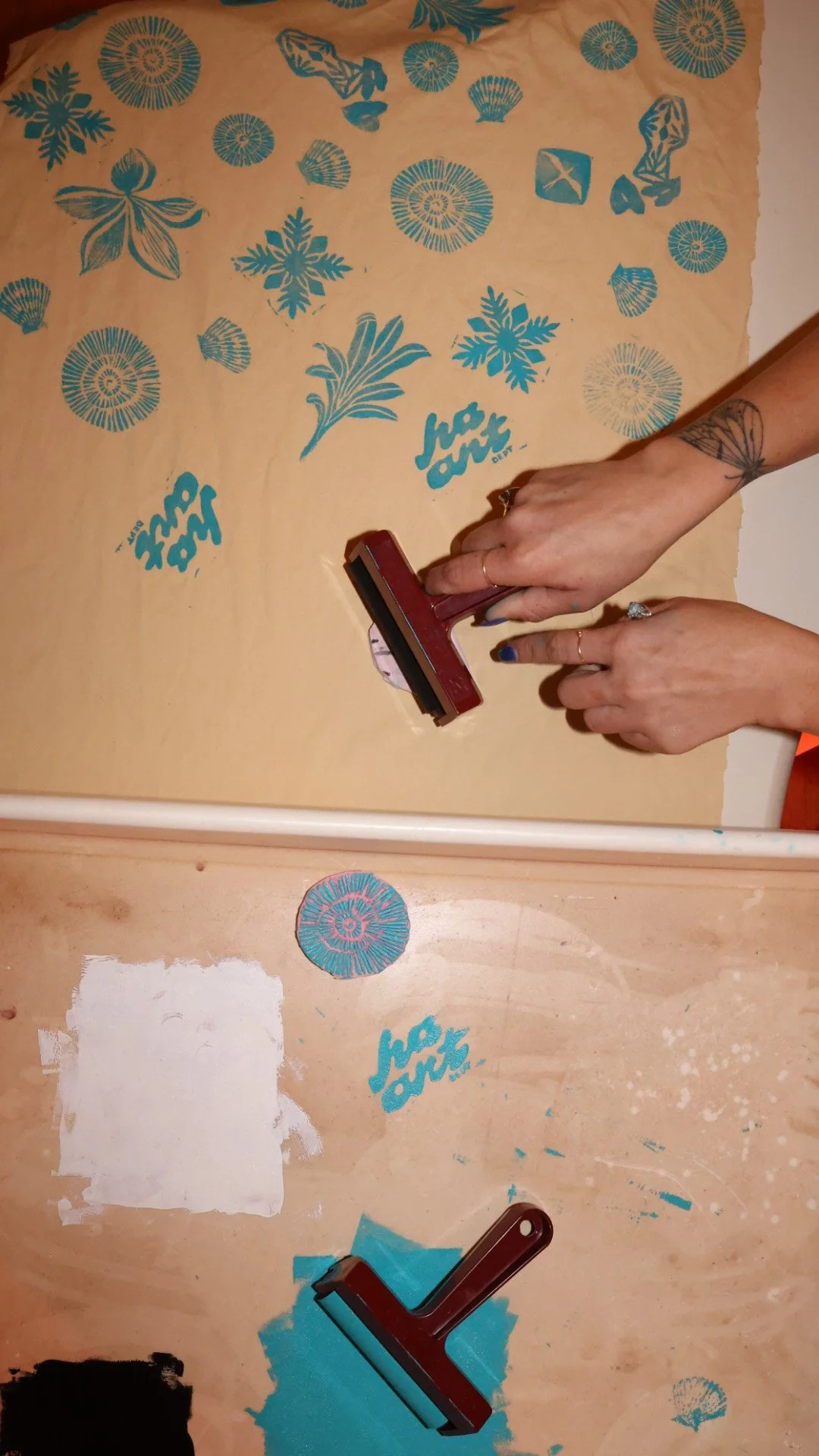 Hands block-printing blue botanical stamps onto canvas