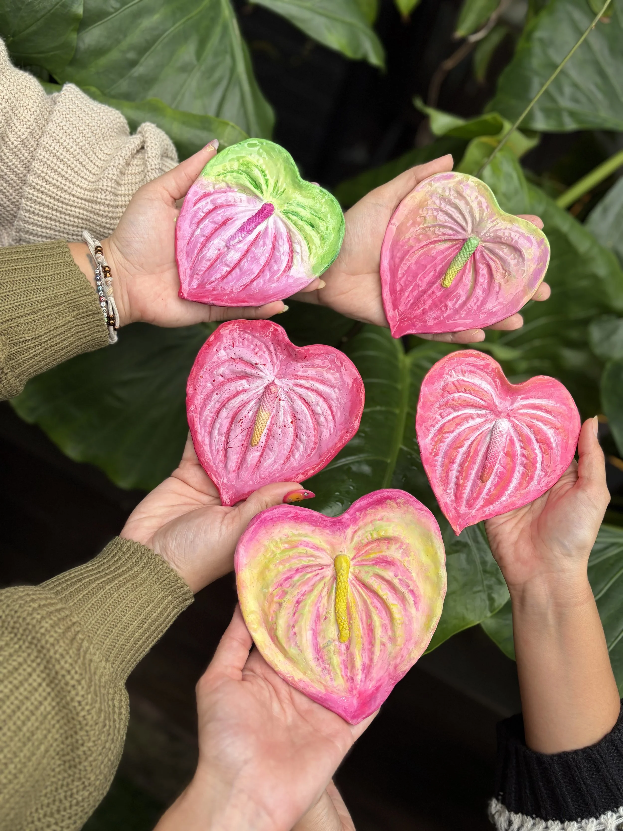 Hands holding painted pink anthurium ring dishes