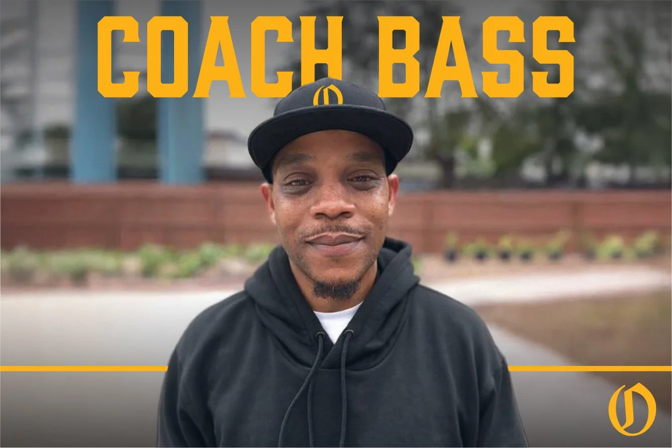 Portrait of a man wearing a green jacket and a white cap, standing outdoors with a blurred background, text overlay reads 'Coach Bass' in large yellow letters.