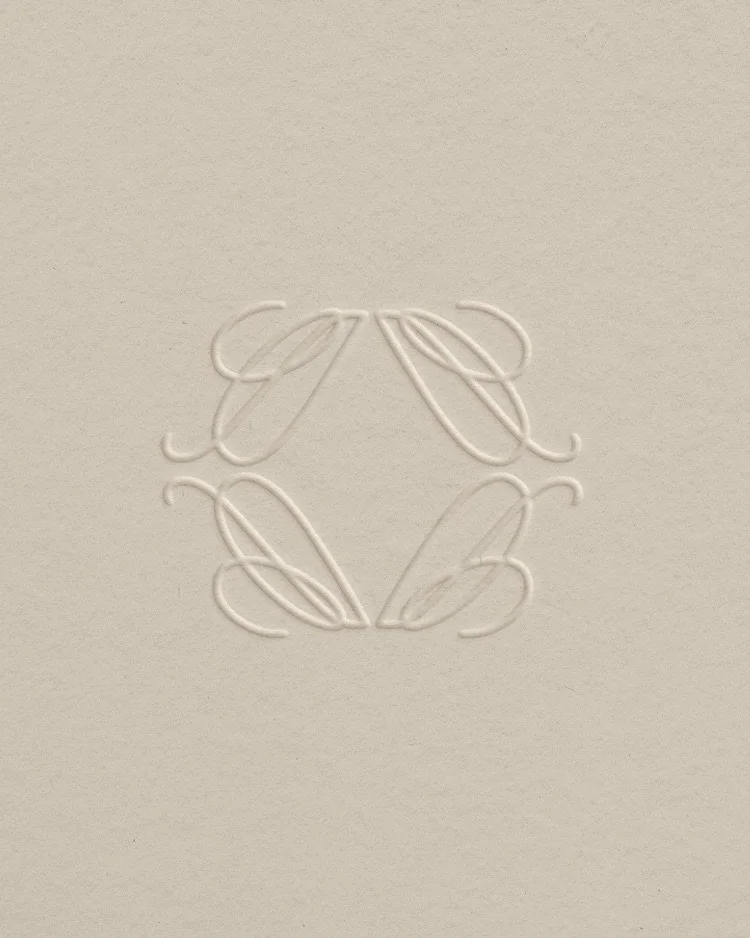 Embossed monogram of the letter 'A' on a beige background.