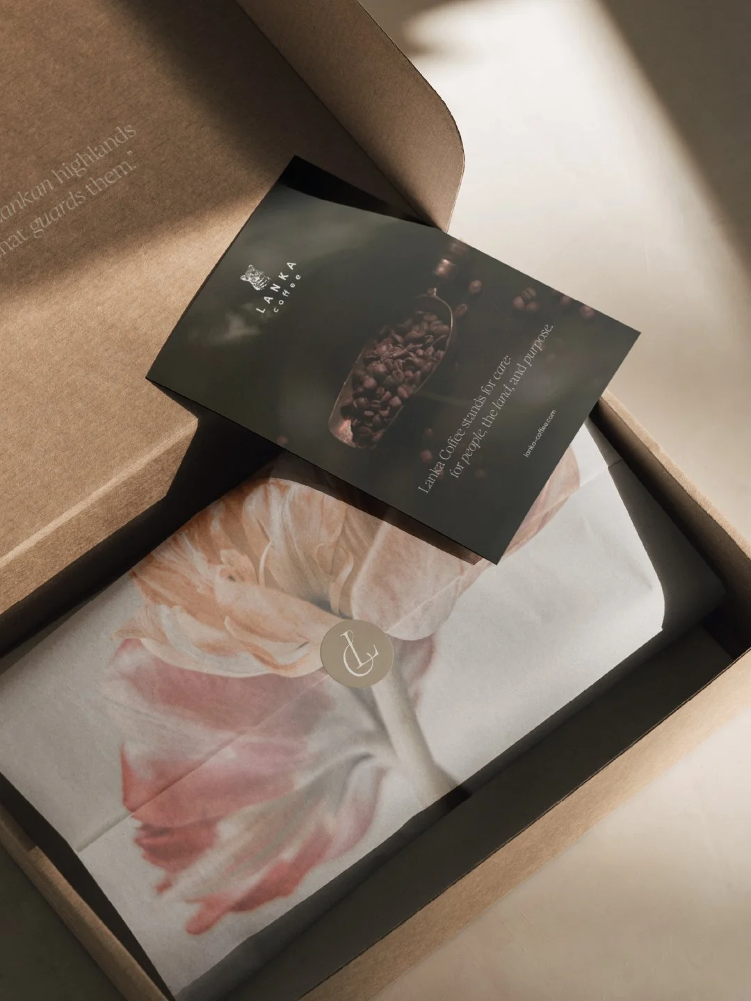 Image of a karton shipment box, featuring a branded Lanka Coffee giftcard, branded sticker with the Lanka Coffee monogram and tissue paper with a tulip picture from Floortje Louise Photography