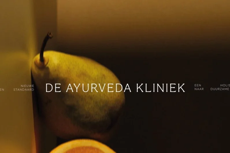 A close-up of a pear and half an orange on a dark surface with Dutch text overlay. 