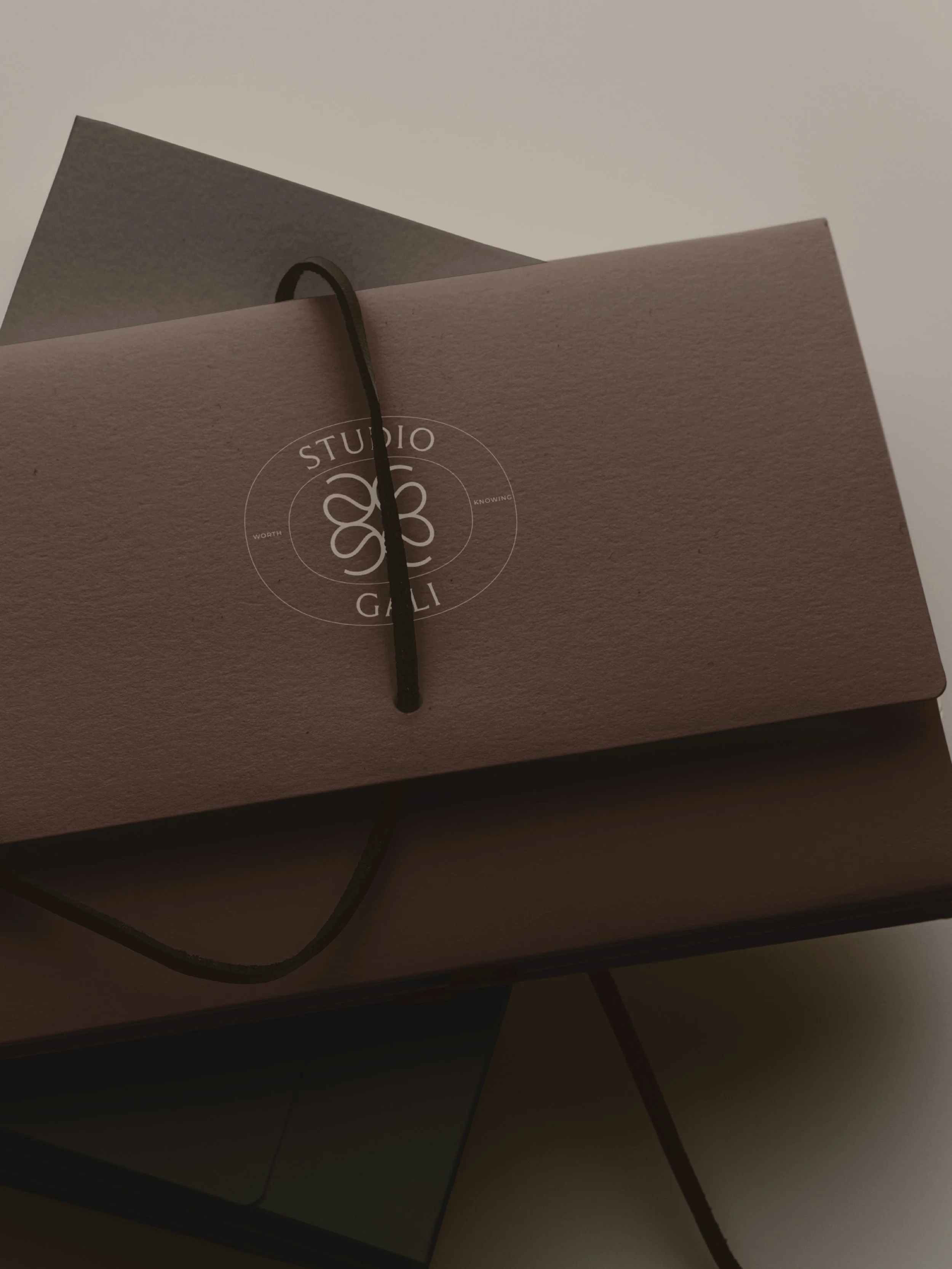 A white sheet with the word 'OUTLINED' at the top, containing a faint circular outline and grid. The sheet has labels 'DOCTOR-LED,' 'AESTHETIC,' and 'REFINEMENT' at the top and a small logo of a circle divided into sections at the bottom.