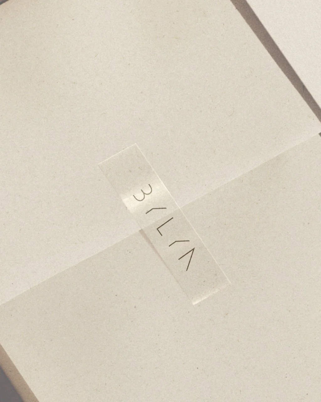 Close-up of a white surface with a transparent tape label that has handwritten letters 'LYK' and the number '3' on it.