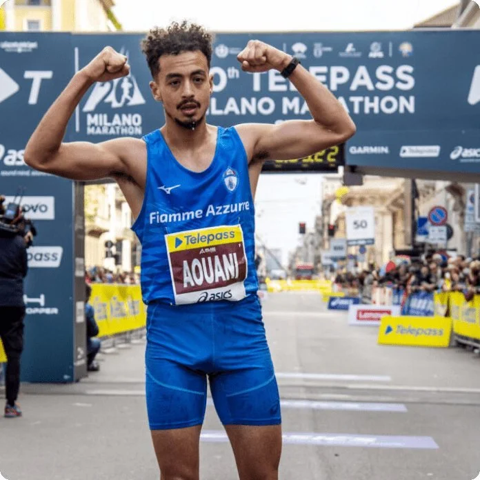 Male marathon runner flexing arms at finish line during Milano Marathon