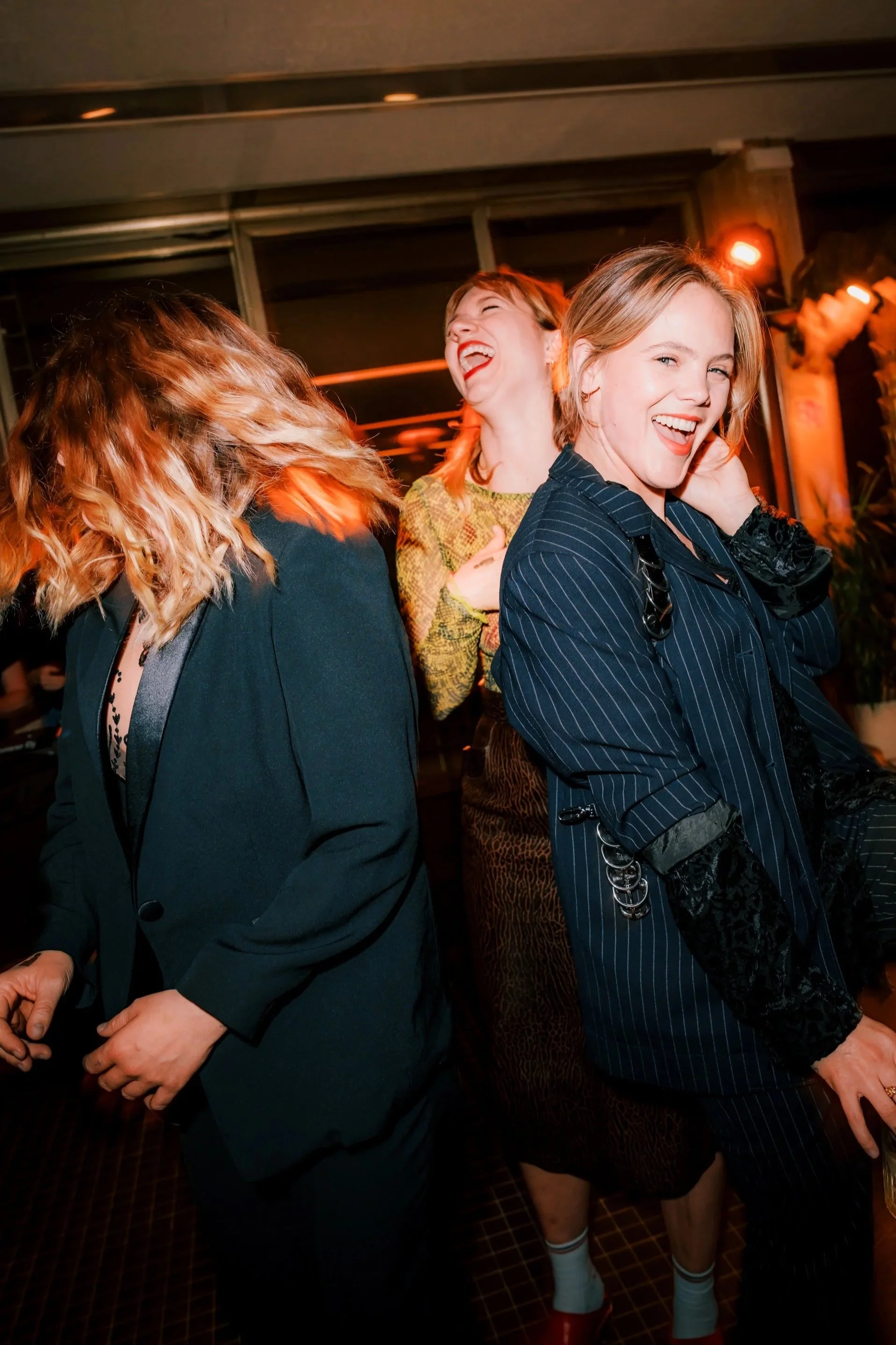 Three women at a lively party, dancing and laughing together.