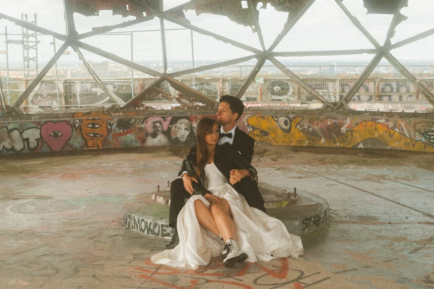 Bride and groom sitting inside Teufelsberg radar dome surrounded by graffiti during urban wedding photoshoot in Berlin