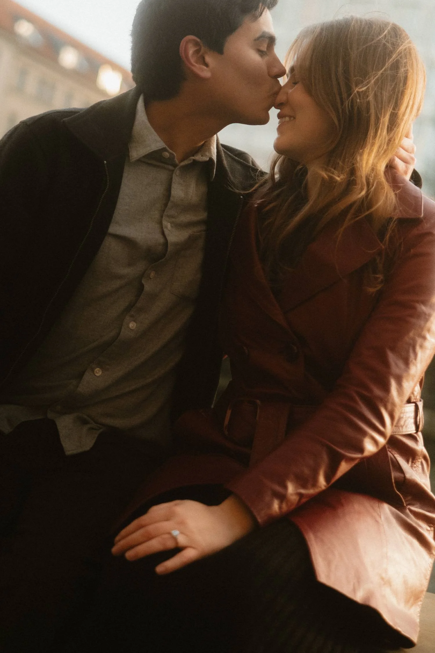 Romantic couple sharing a kiss during golden hour in Berlin, intimate engagement moment outdoors