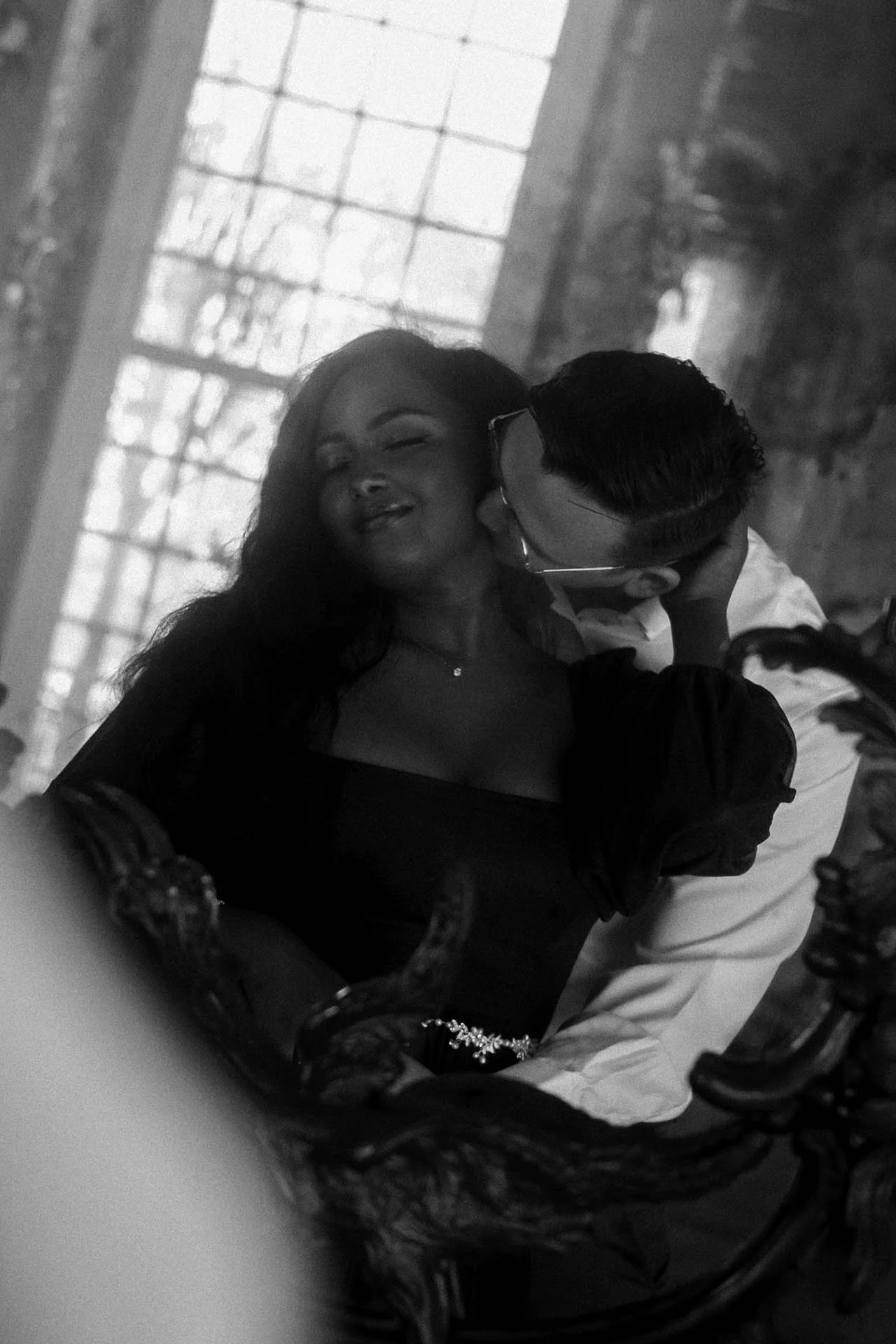 An intimate and romantic moment between an engaged couple captured in the majestic Charlottenburg Palace, Berlin. The natural light streaming through the grand windows enhances the timeless beauty of this historic venue, creating a soft, warm ambianc