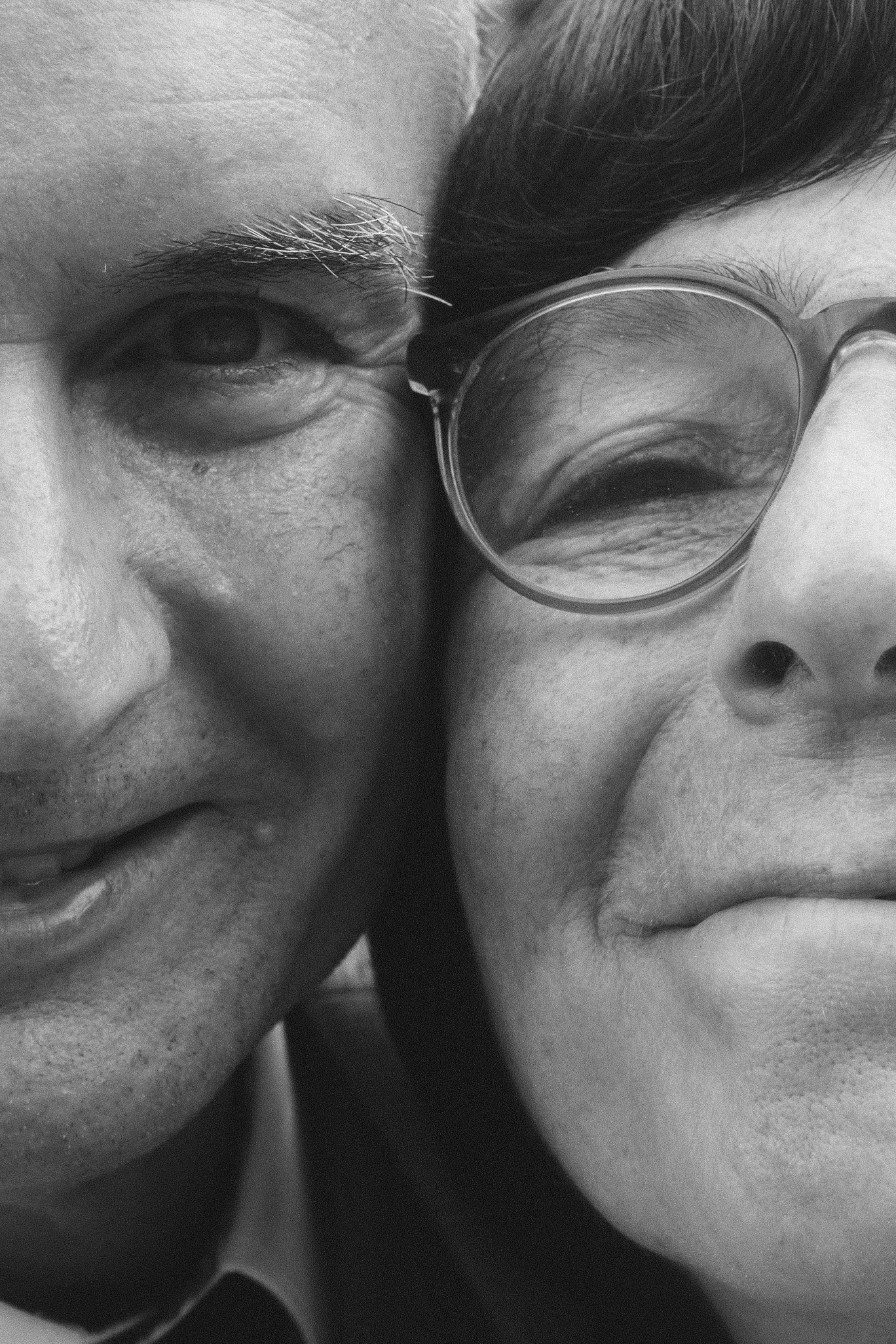 A black and white close-up portrait of the smiling wedding couple's faces pressed together.