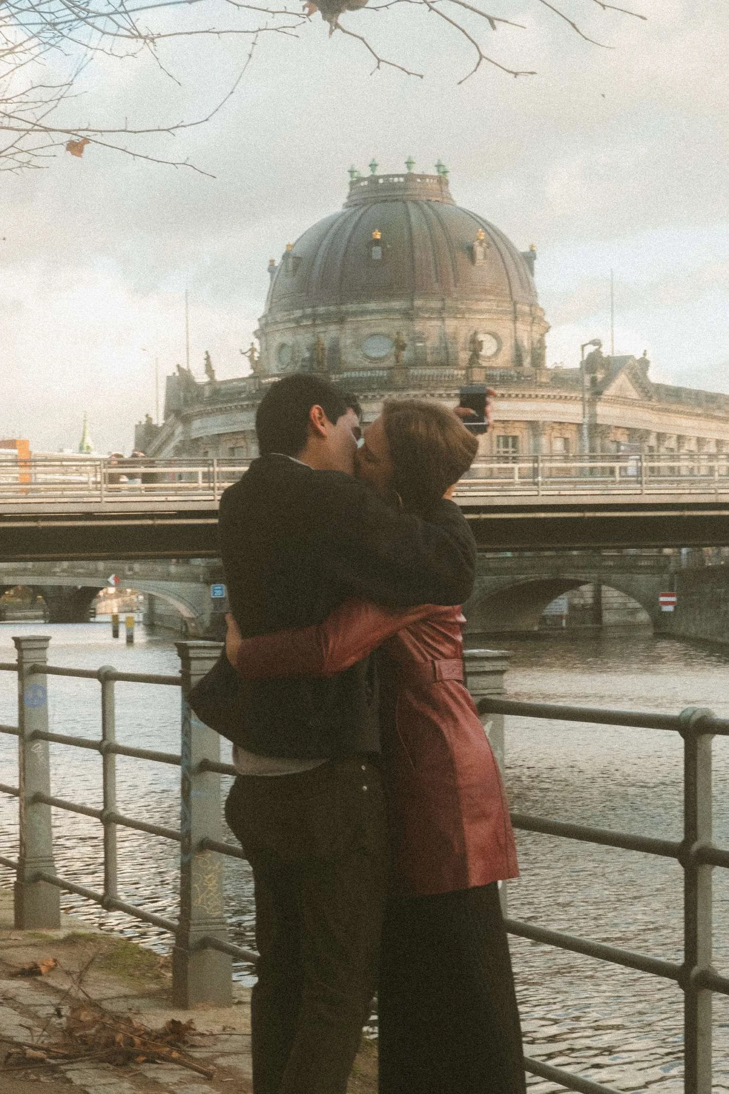 Romantic couple kissing by the river in front of Bode Museum on Museum Island in Berlin.