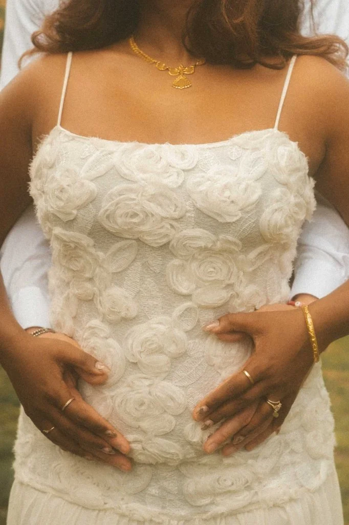 A close-up detail shot of a couple's hands resting on a textured floral engagement dress during a professional photoshoot in Berlin.