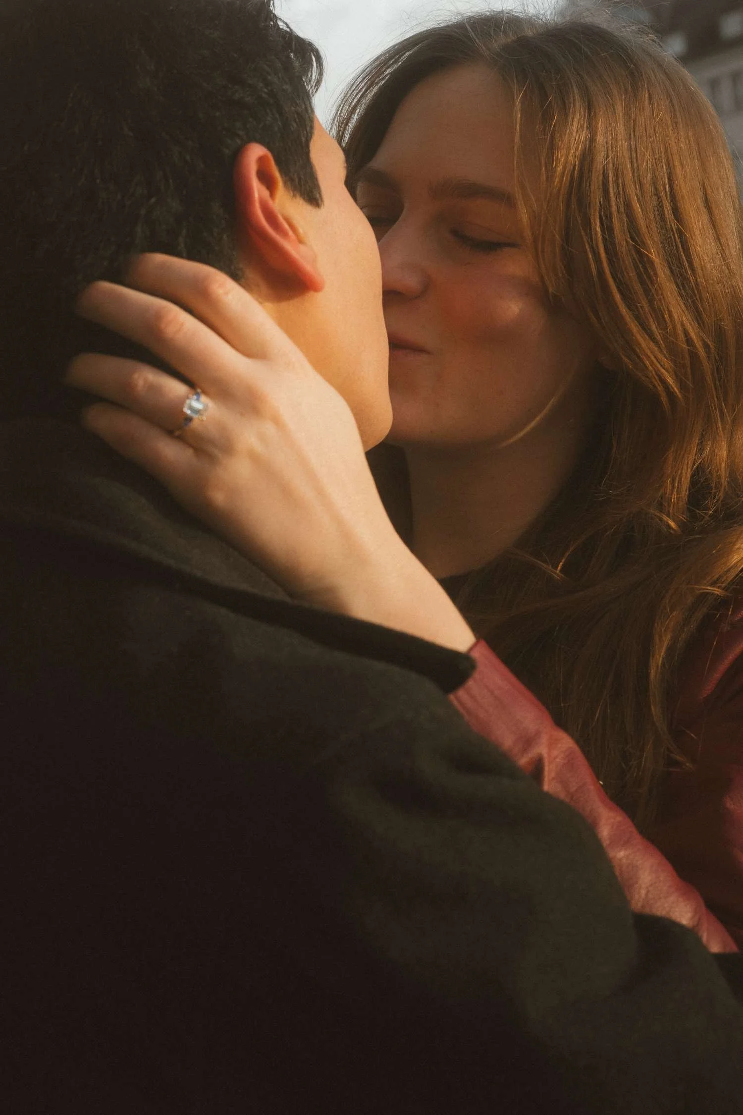 Couple sharing an intimate kiss after a surprise proposal on Museum Island in Berlin, engagement ring visible