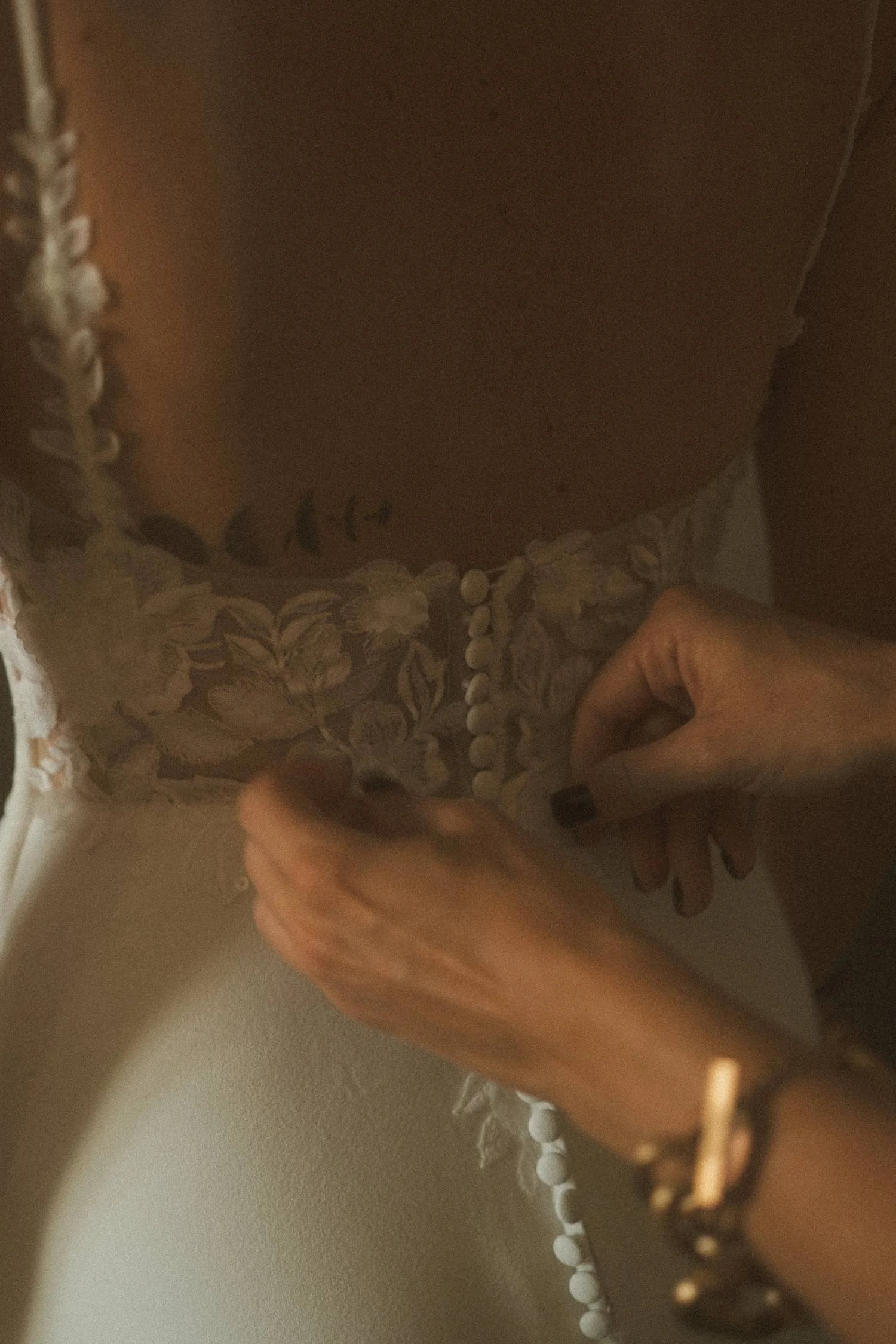 Bride fastening lace wedding dress buttons during intimate bridal preparation in Berlin.