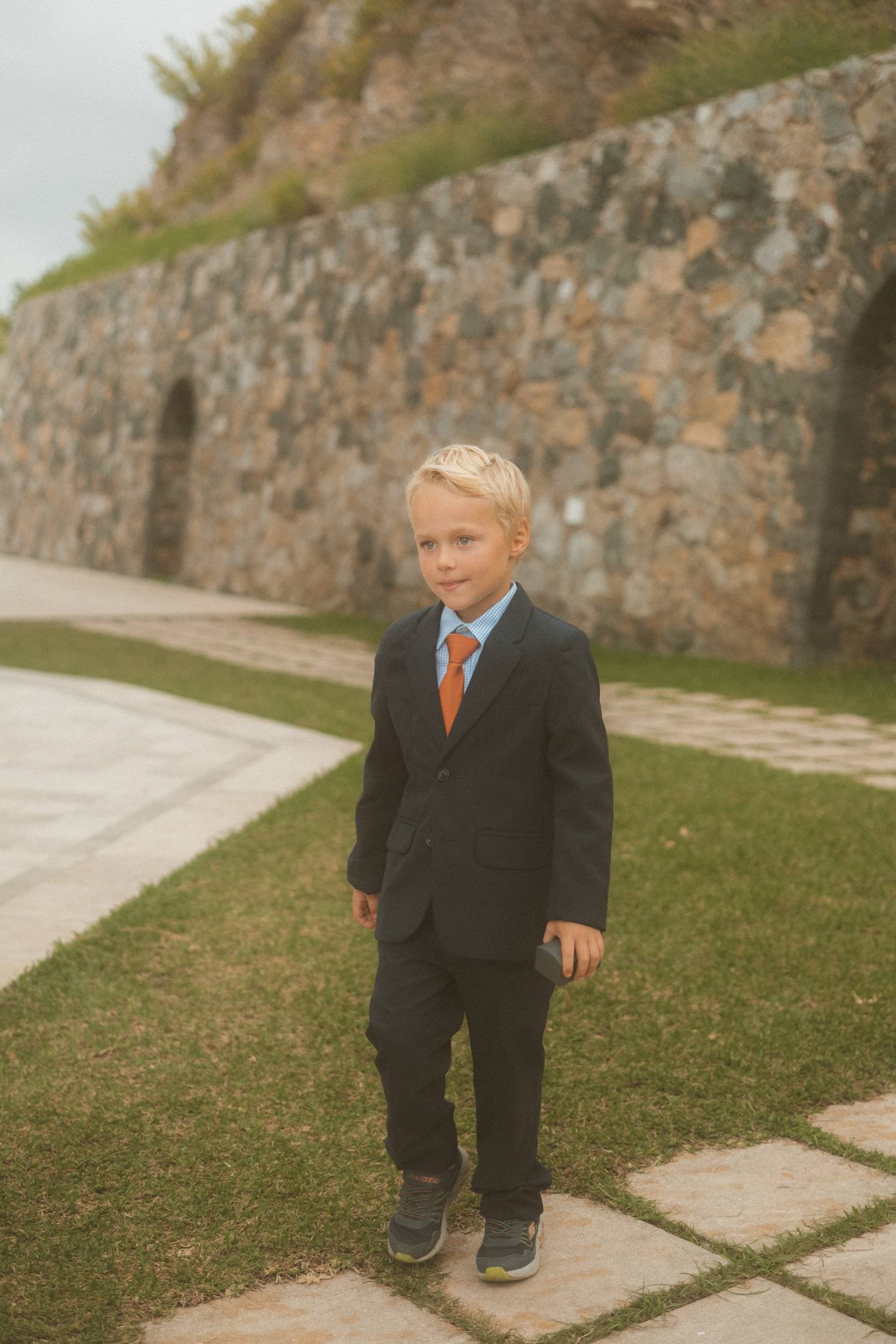 Young boy in a suit walking outdoors during a wedding ceremony