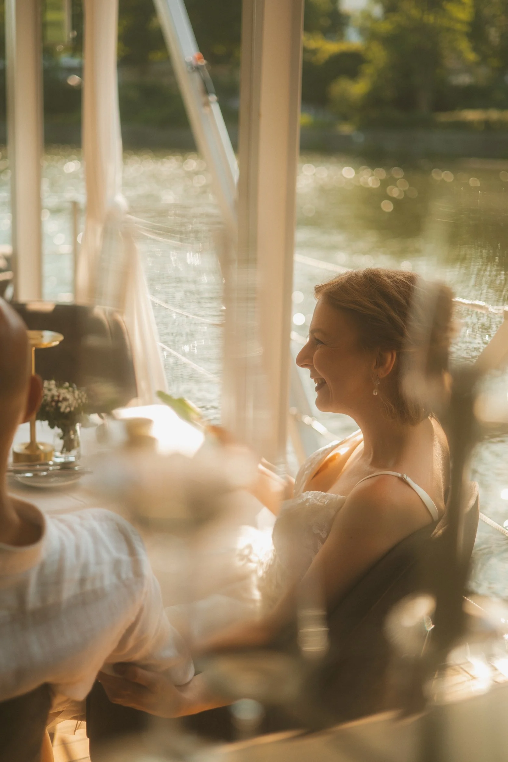 Candid portrait of bride laughing joyfully at reception table at a Berlin waterside venue