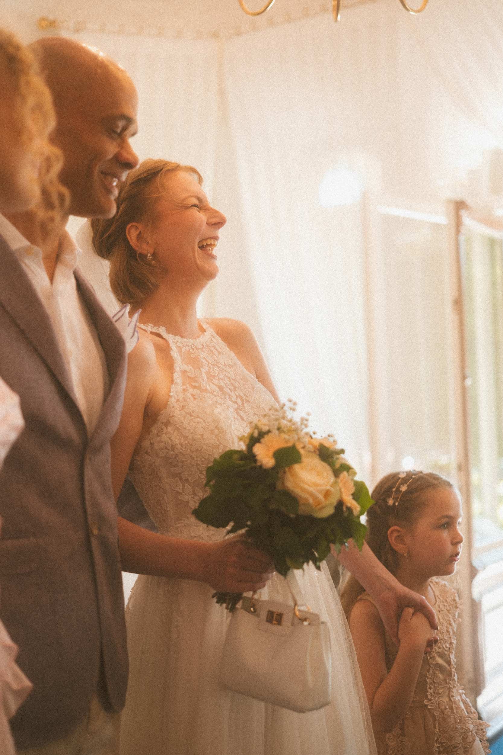 Couple laughing joyfully with flower girl during Berlin Standesamt civil wedding ceremony