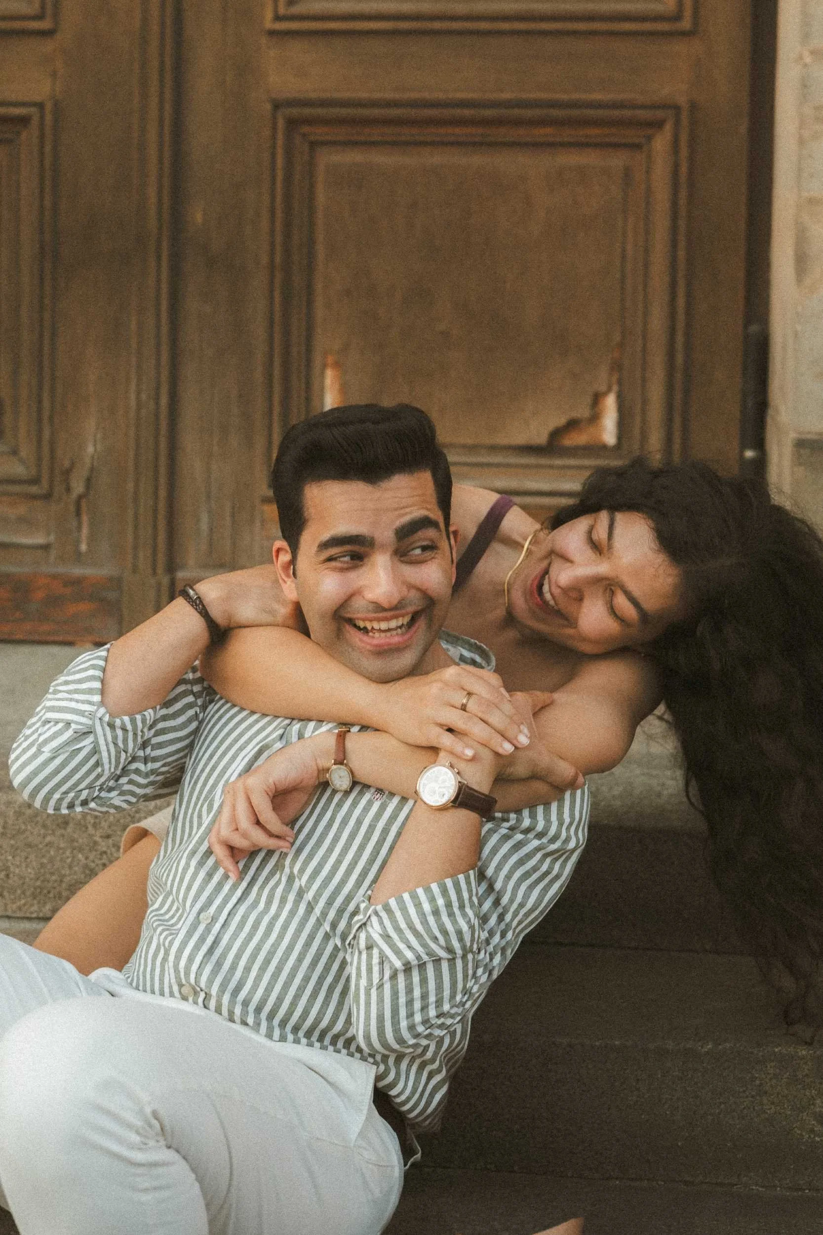 A candid, joyful photograph of a couple embracing and laughing on the steps of the Bode Museum during their Berlin engagement session.
