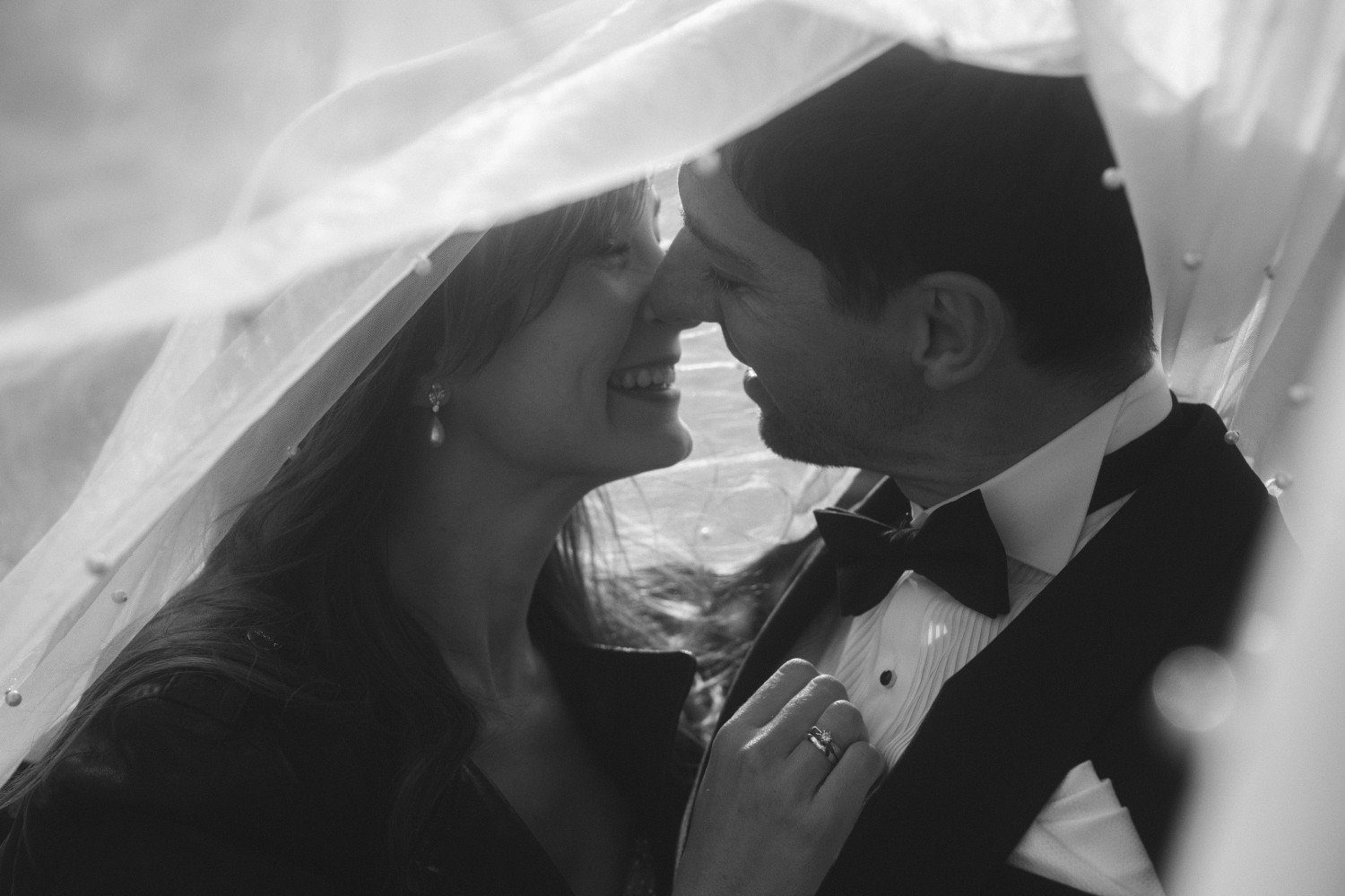 Black and white photo of bride and groom kissing under veil during wedding photoshoot at Teufelsberg Berlin
