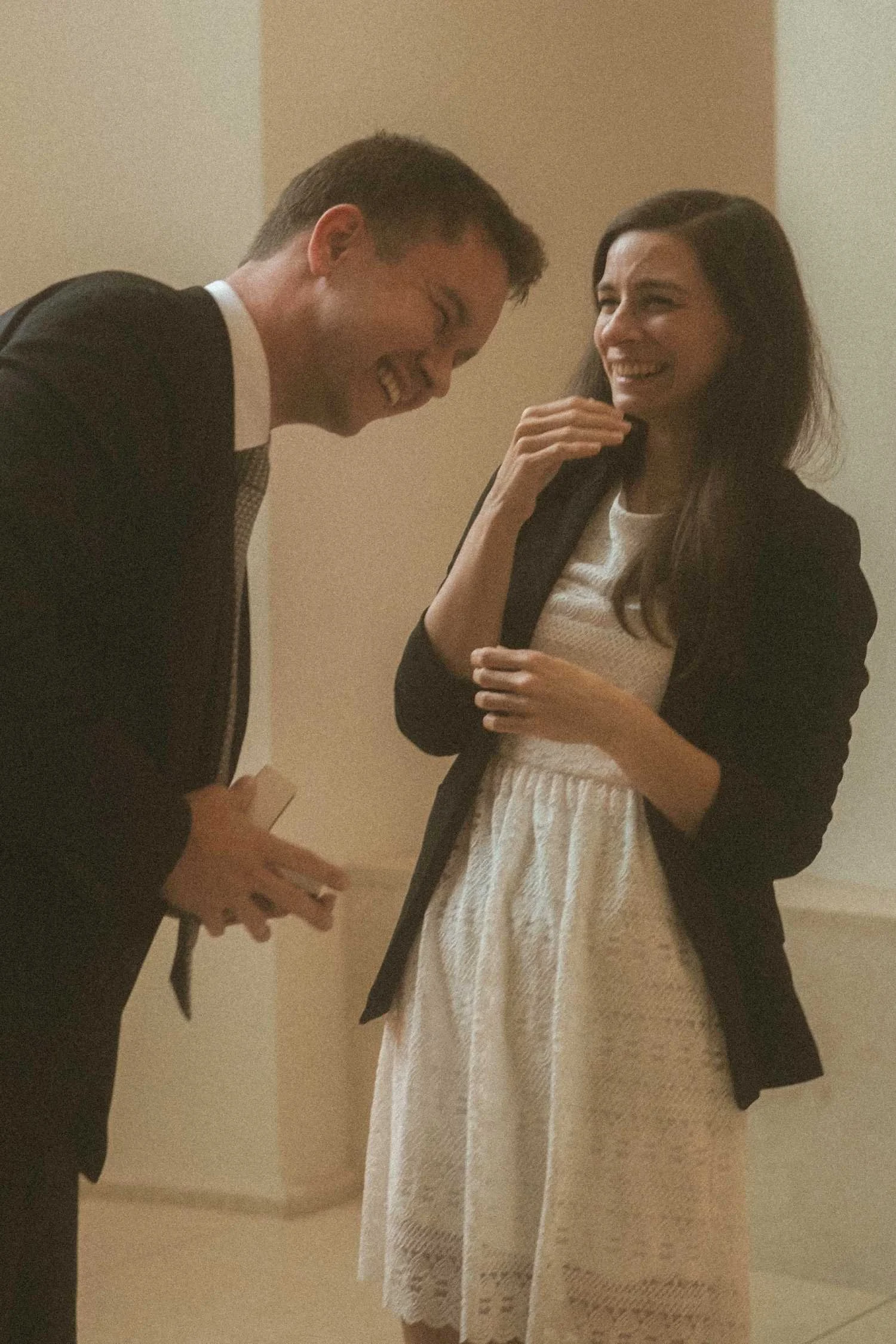 Emotional reaction during surprise proposal in Berlin with man holding ring box indoors