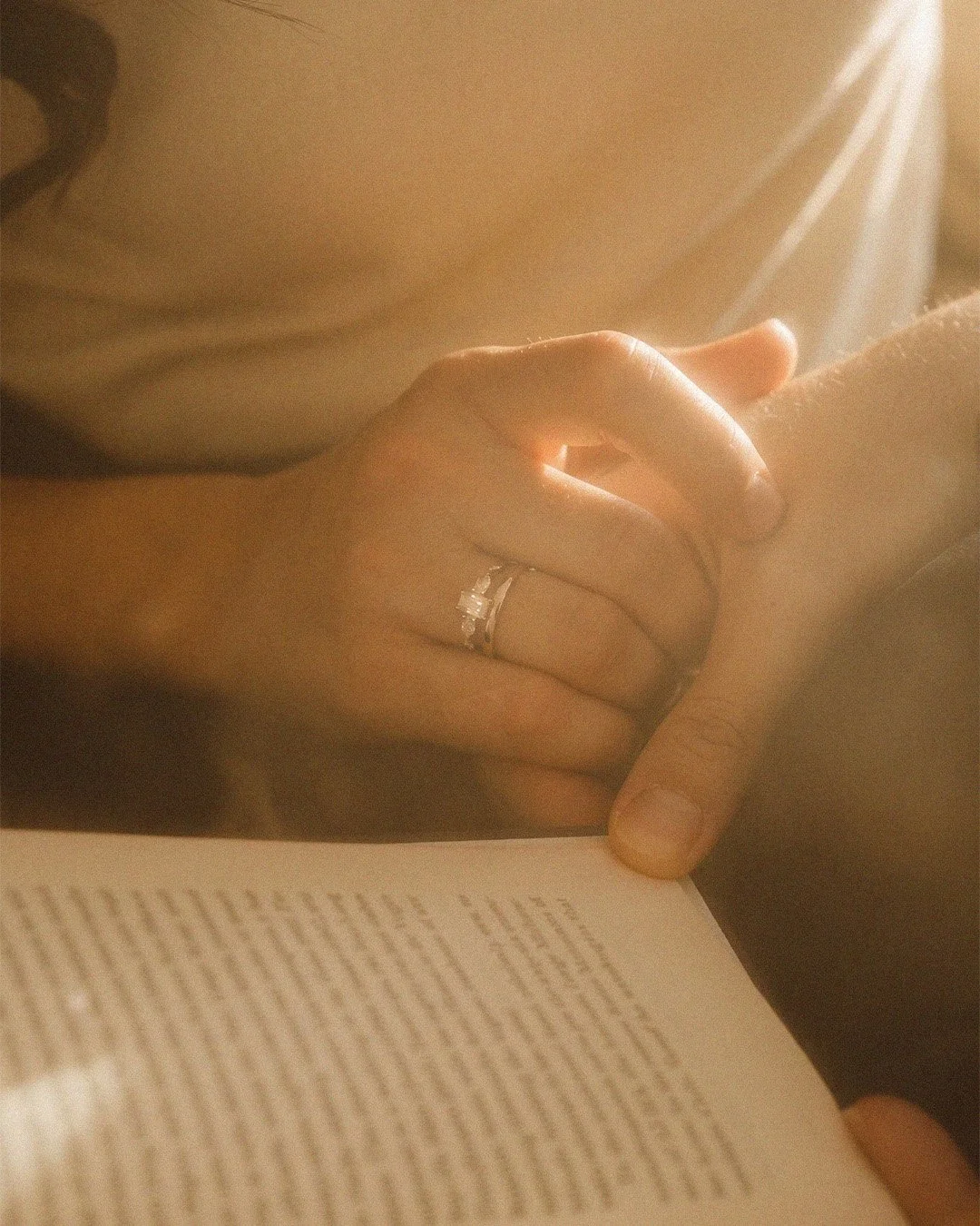Detail shot of an engagement ring on a woman's hand while reading a book in a Berlin apartment.