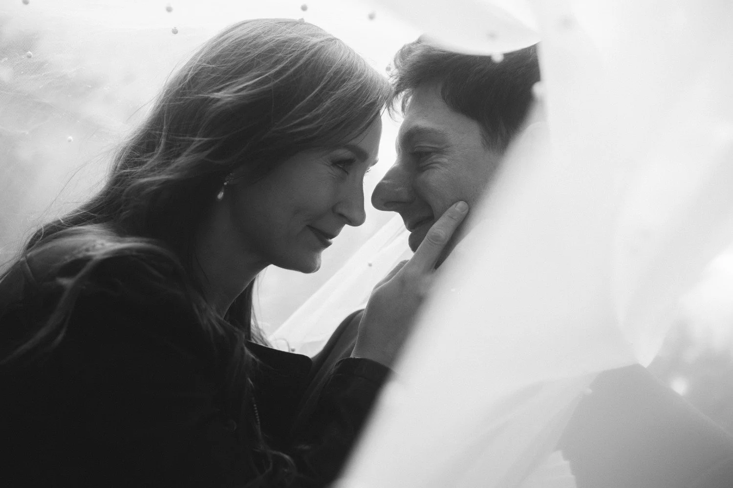 Black and white close-up of bride touching groom’s face under veil during wedding photoshoot at Teufelsberg Berlin