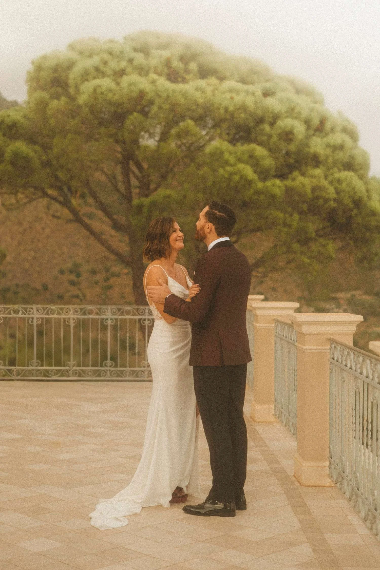 Bride and groom sharing an intimate moment on an outdoor terrace during a destination wedding at sunset.
