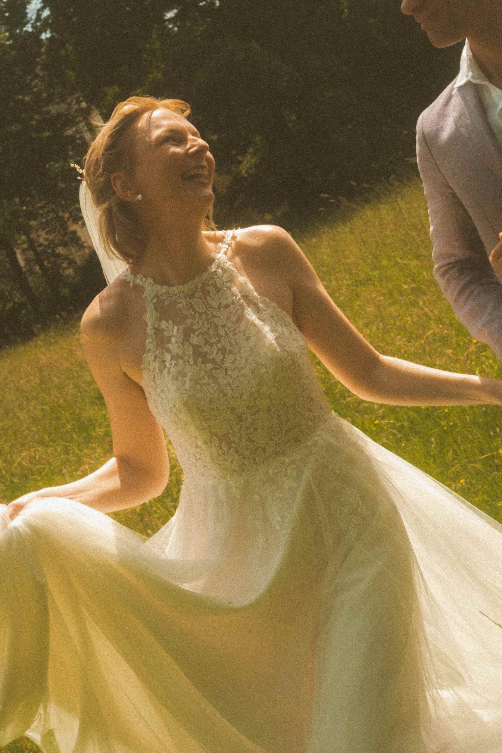 Bride spinning joyfully in her lace wedding dress in golden afternoon light in Berlin park