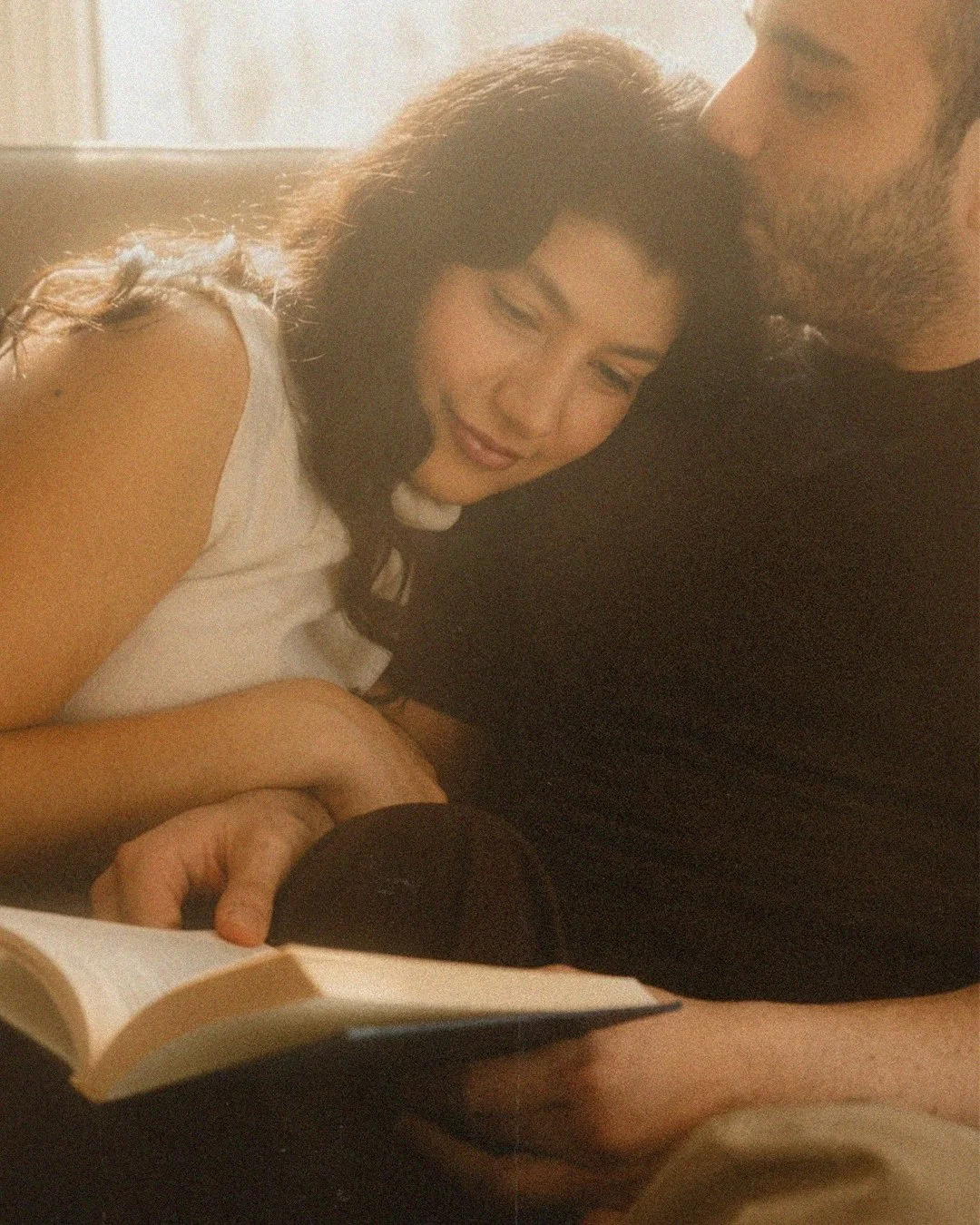 Intimate lifestyle portrait of a couple reading a book together in a Berlin Kreuzberg apartment with warm cinematic light.