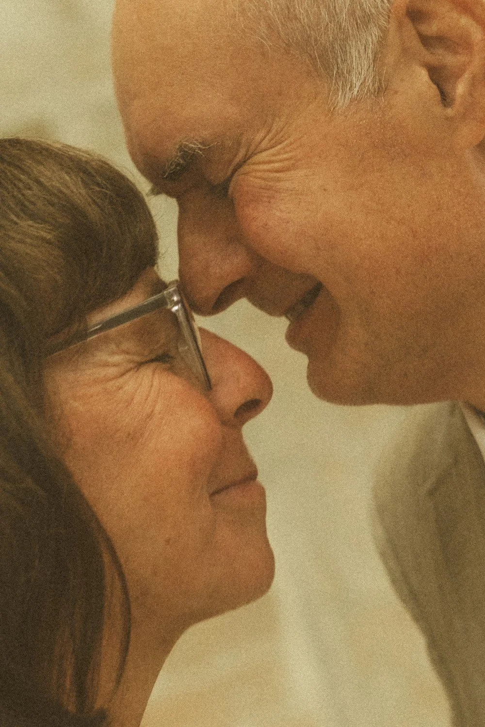 An extreme close-up indoor portrait of the wedding couple smiling with their foreheads touching.
