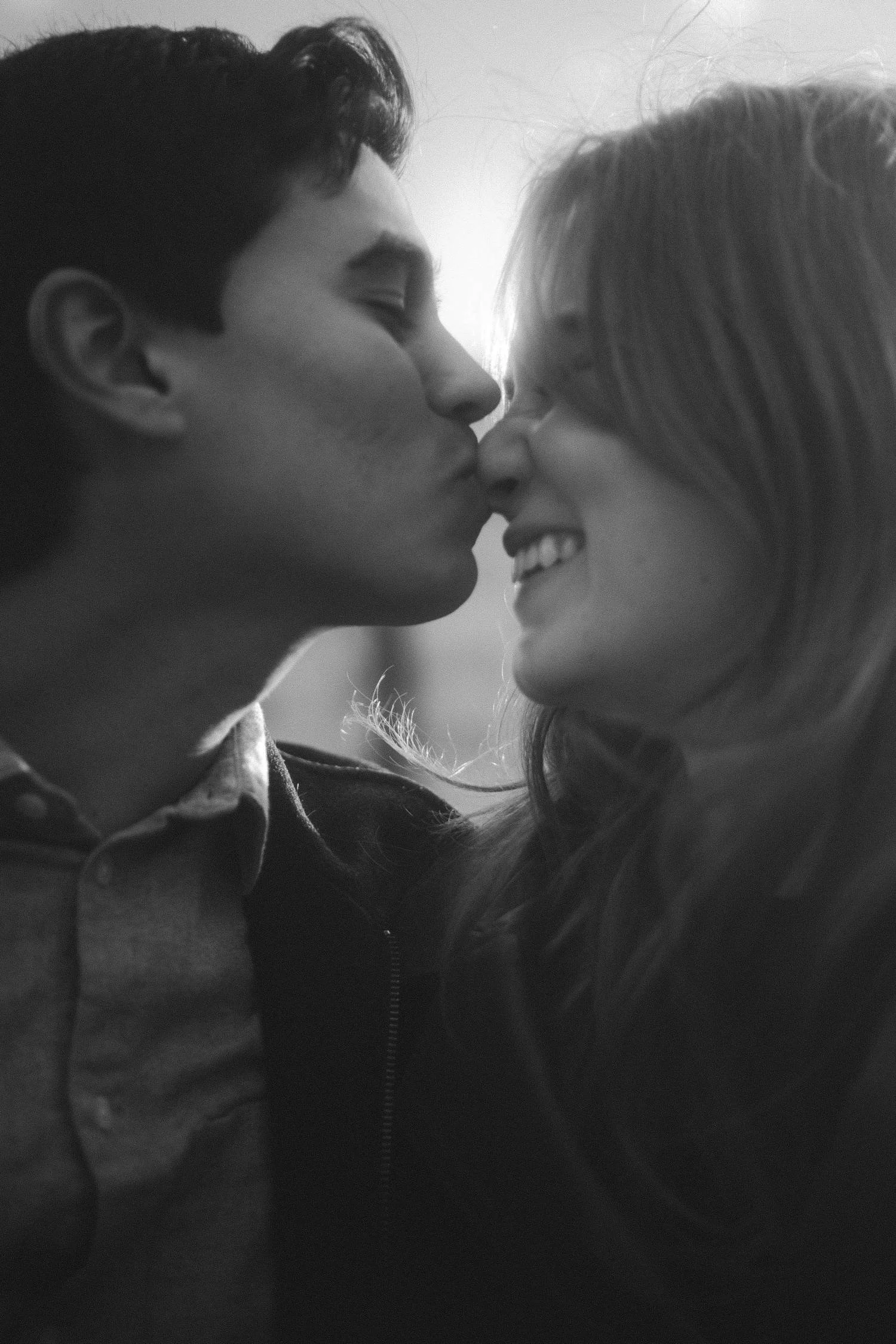 Black and white close-up portrait of a couple sharing a kiss during an intimate moment in Berlin