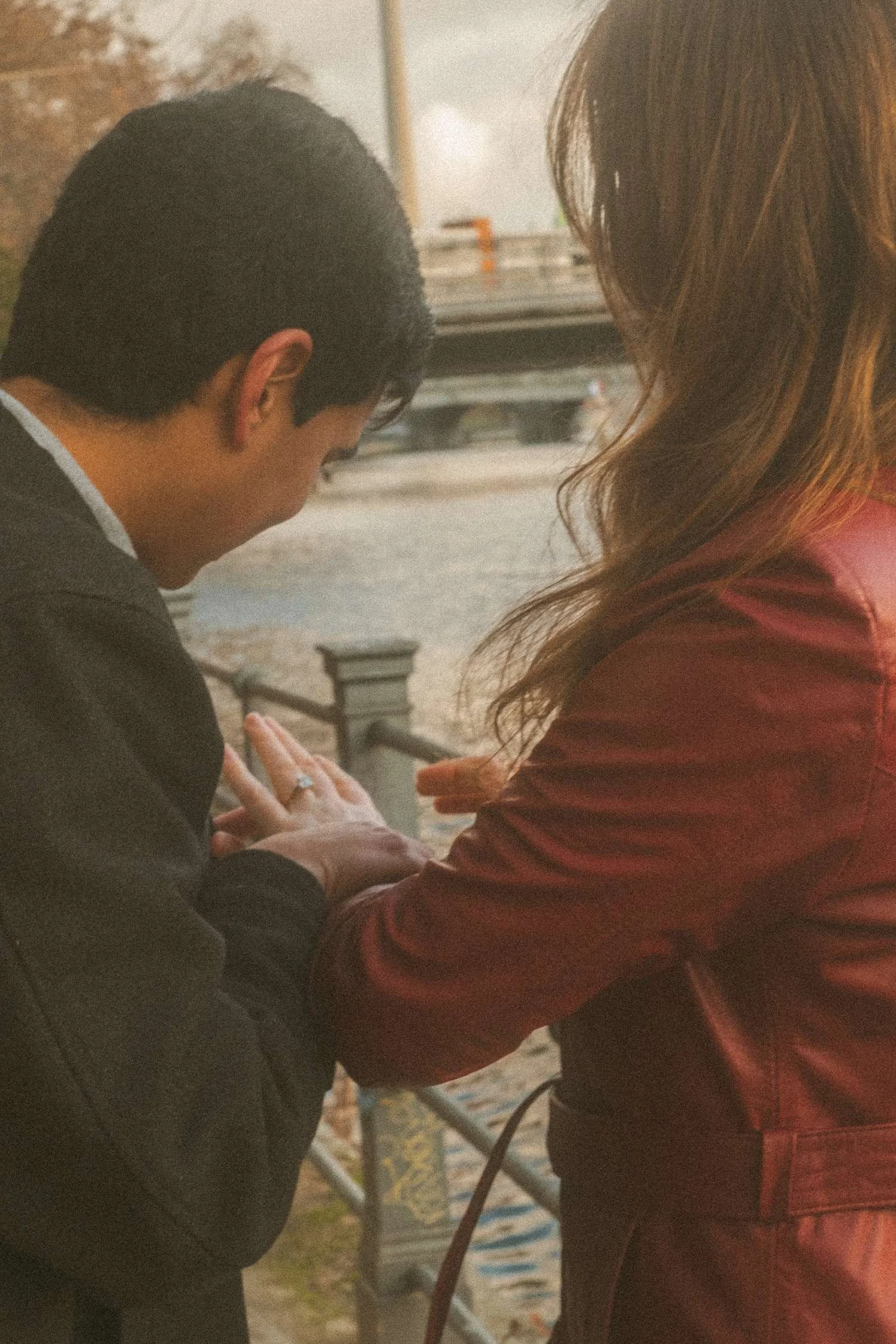 A couple shares an intimate moment after a surprise proposal by the river in Berlin, capturing the engagement ring and raw emotion.