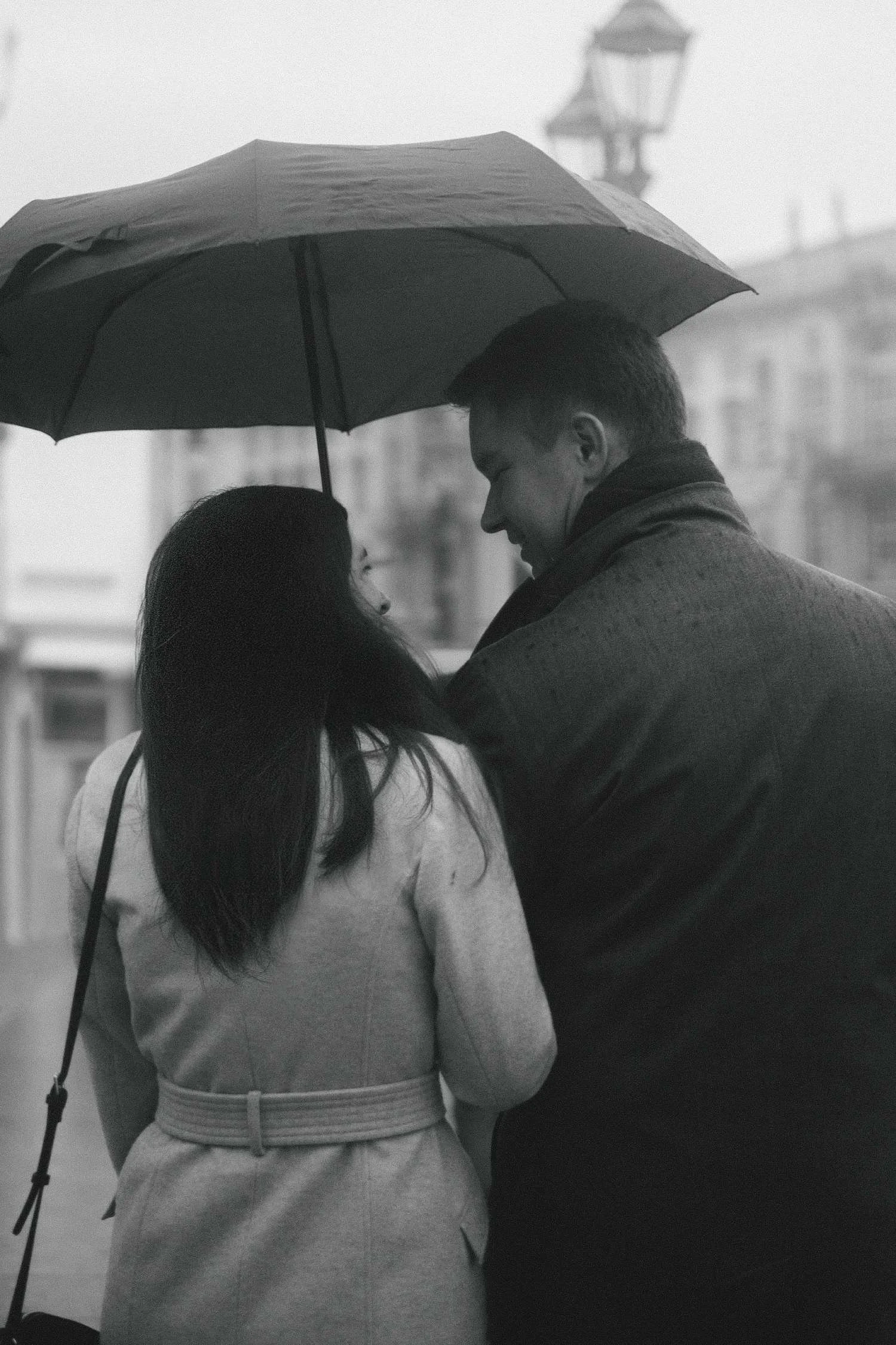 Black and white photo of couple under umbrella in the rain during romantic Berlin portrait photoshoot