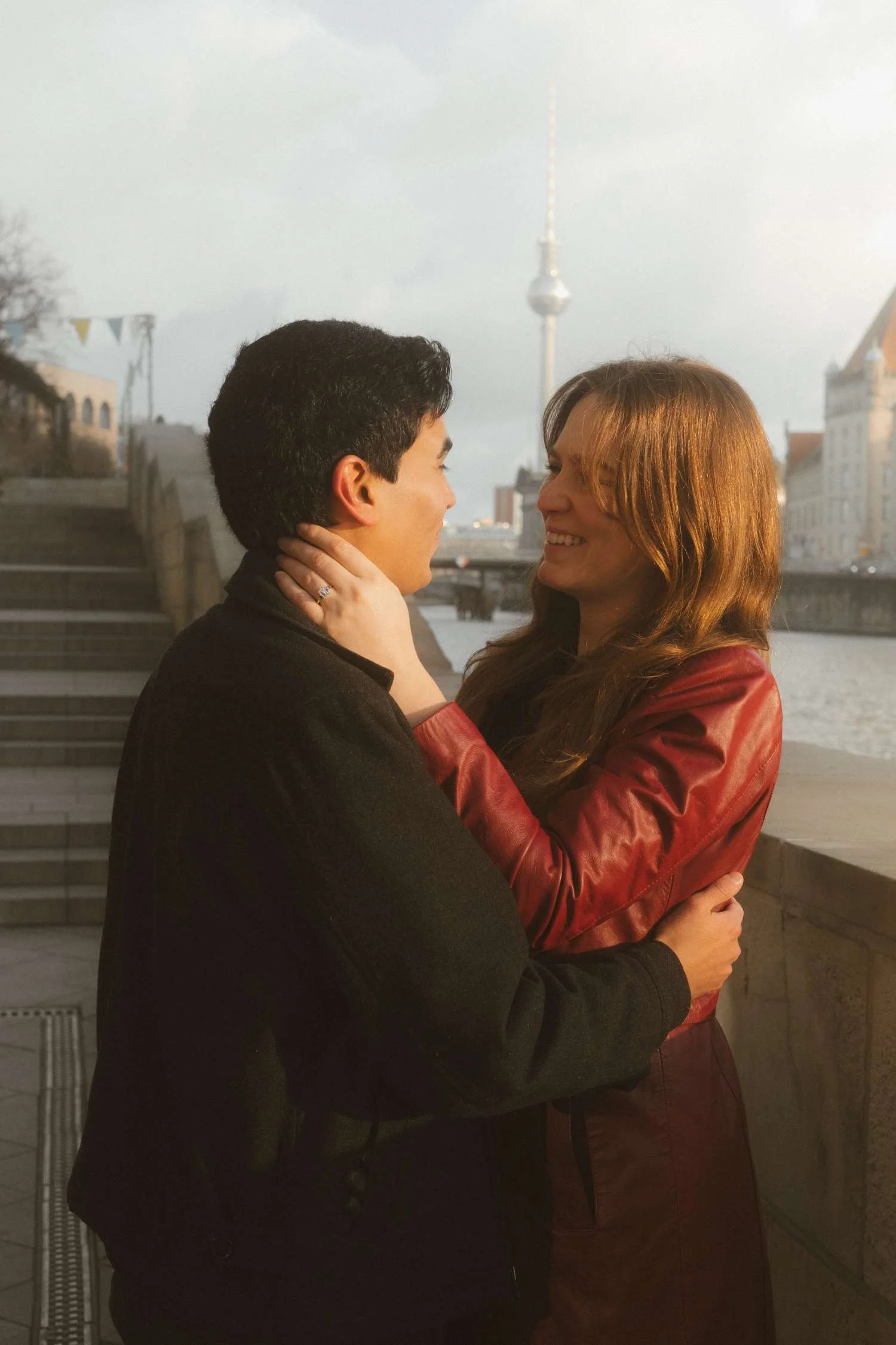 Couple embracing near Museum Island in Berlin with TV Tower in the background during golden hour