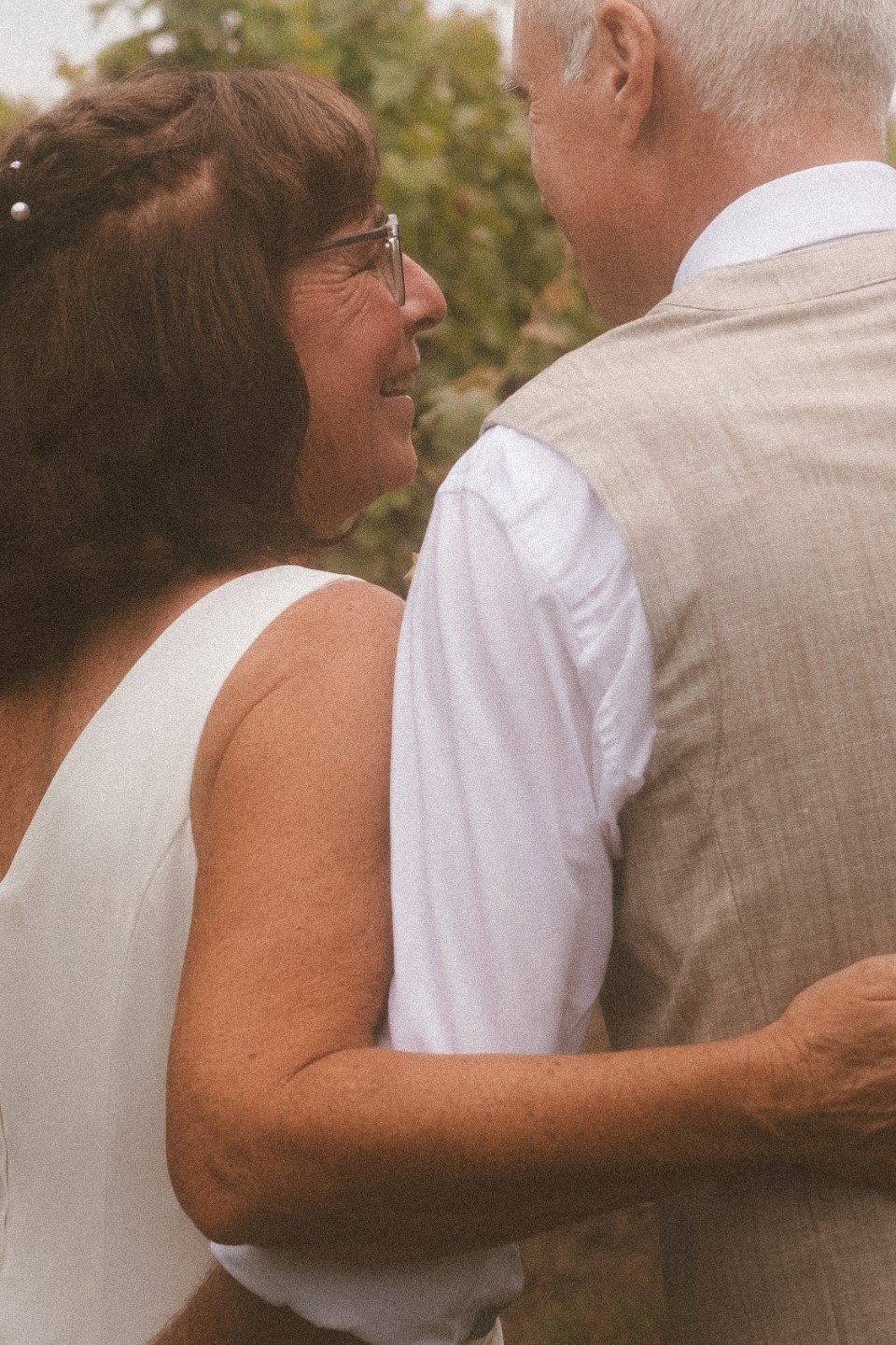 A close-up portrait of the bride and groom hugging outdoors.