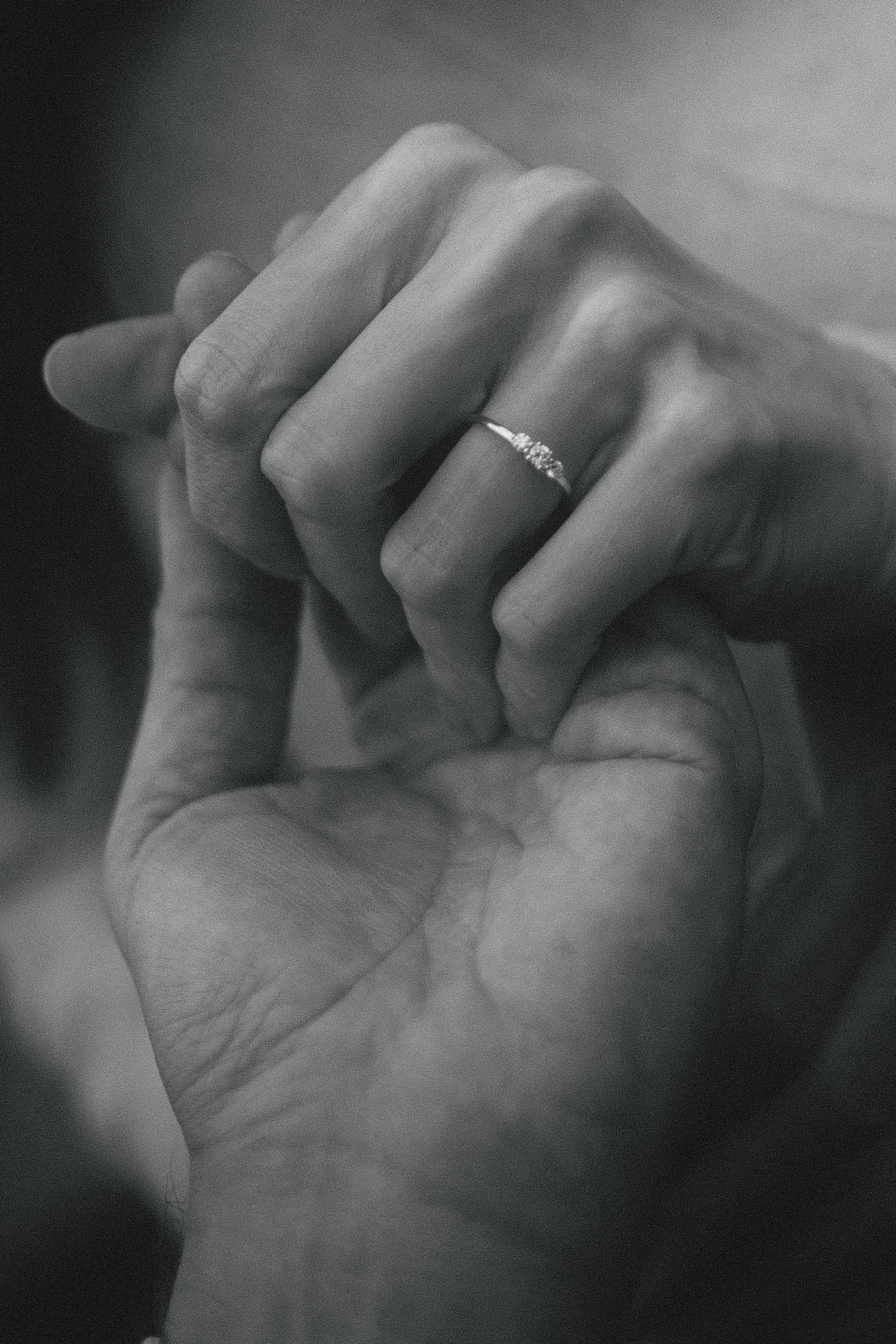 Close up black and white photo of engagement ring on couple holding hands during Berlin photoshoot