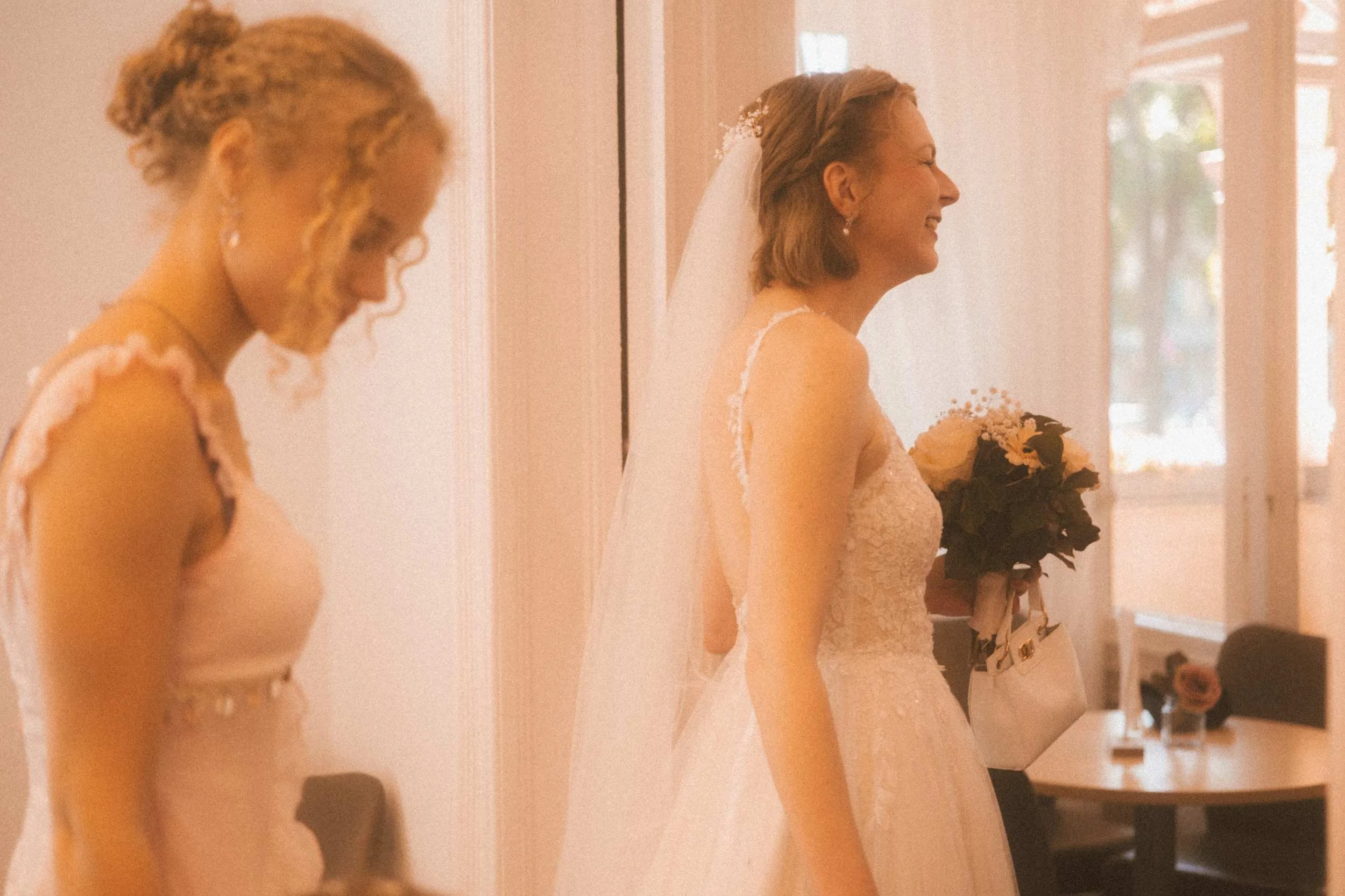 Bride holding white bouquet inside Berlin Standesamt smiling with bridesmaid before civil ceremony