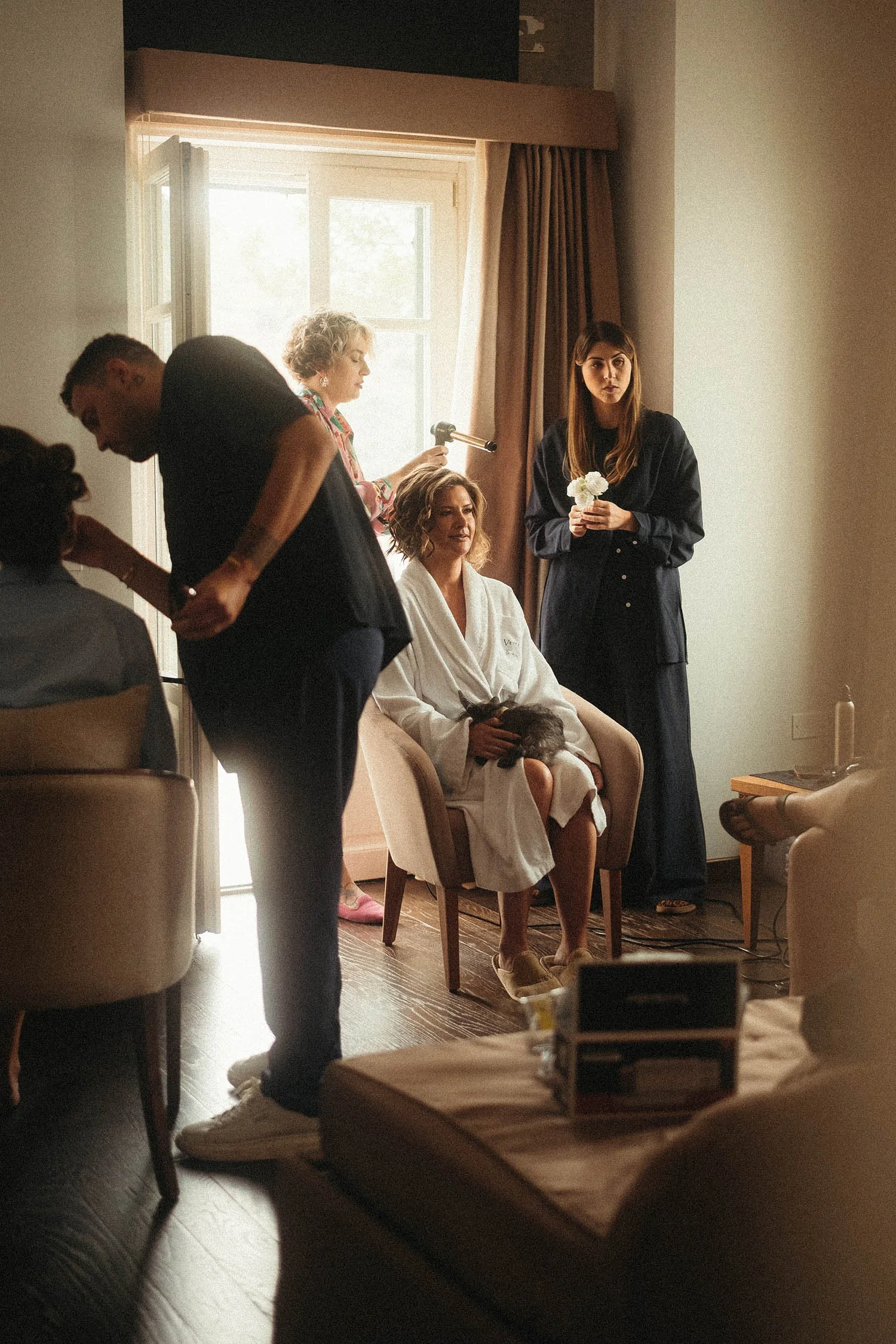 Bride surrounded by friends and stylists during wedding morning preparation in Sicily, candid destination wedding getting-ready moment.